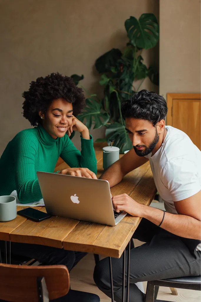  A man and a woman sitting at a table looking into a laptop