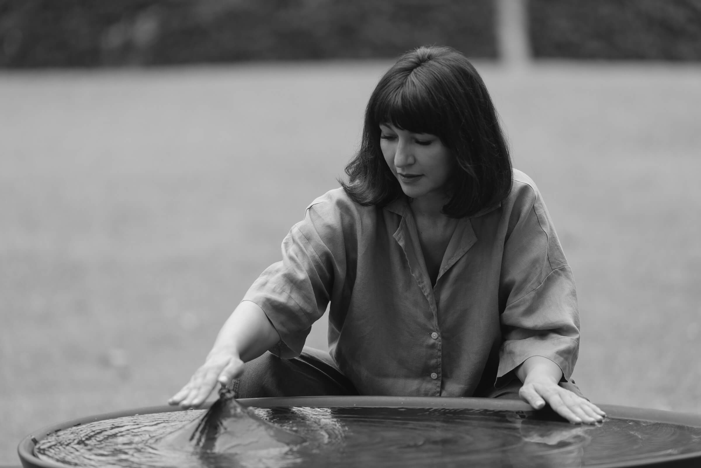 Ina MacKinnon, founder of Homebridge Alliance, resting her hands in a bowl of water outdoors.