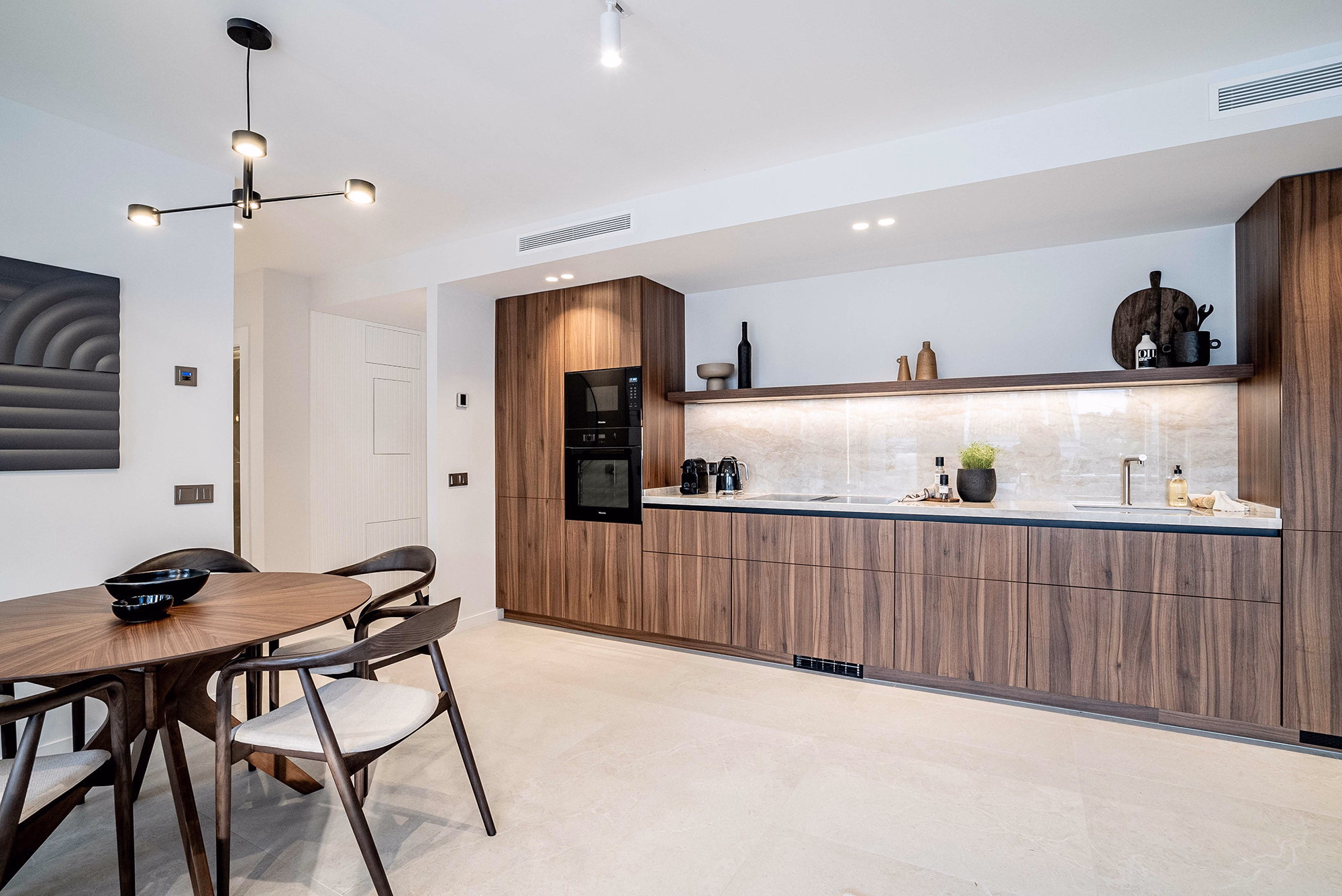 Modern kitchen with walnut wood cabinetry and brushed nickel finishes at Casa Louneh in Marbella