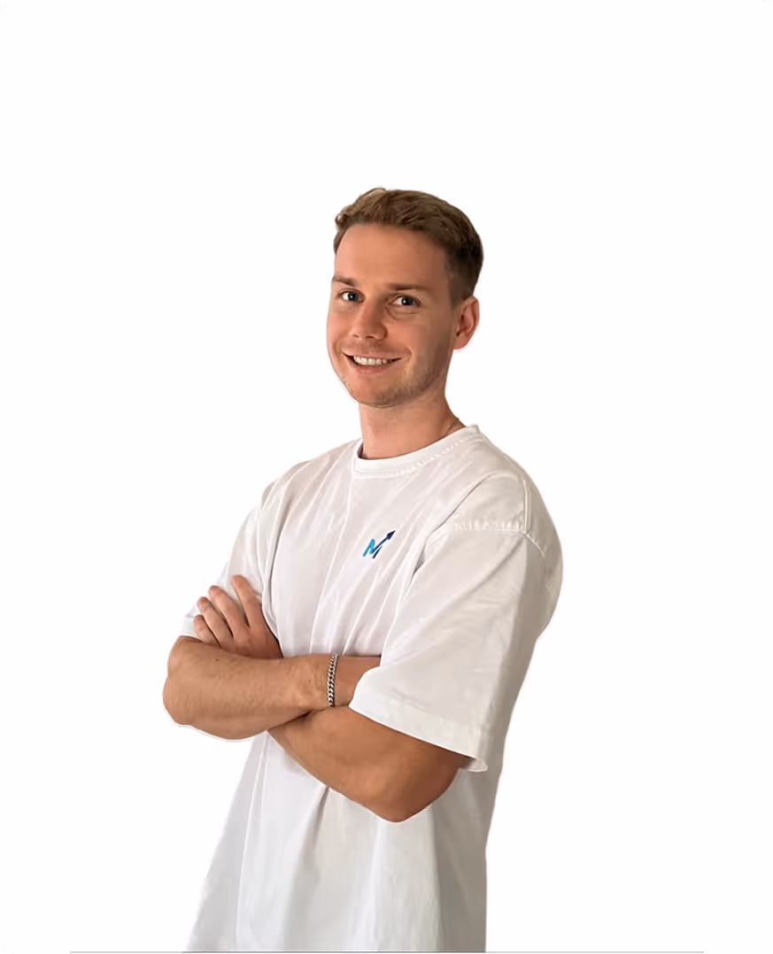 Junger Mann mit weißem T-Shirt lächelt, Arme vor der Brust verschränkt vor weißem Hintergrund.