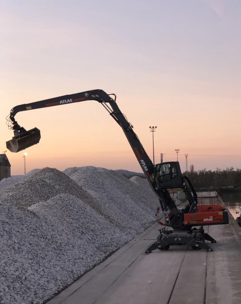 Déchargement d'une péniche de dolomite (matériau utilisé dans la fabrication de laine de roche) par une pelle de manutention Atlas 350MH