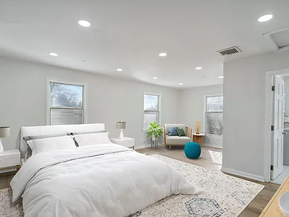 Private bedroom sober living room on display with large white bed and white painted walls and ceiling.