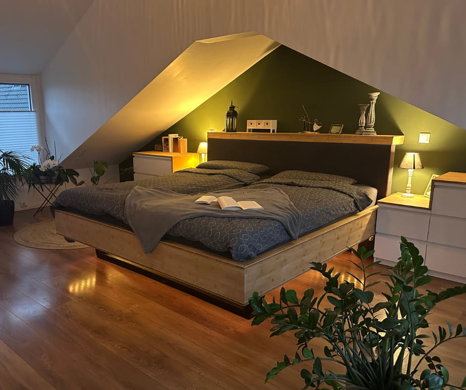 Natürliche Farbtöne mit grün und braun und Holzbett im Schlafzimmer. Unikatbau aus Holz bei Kernfokus