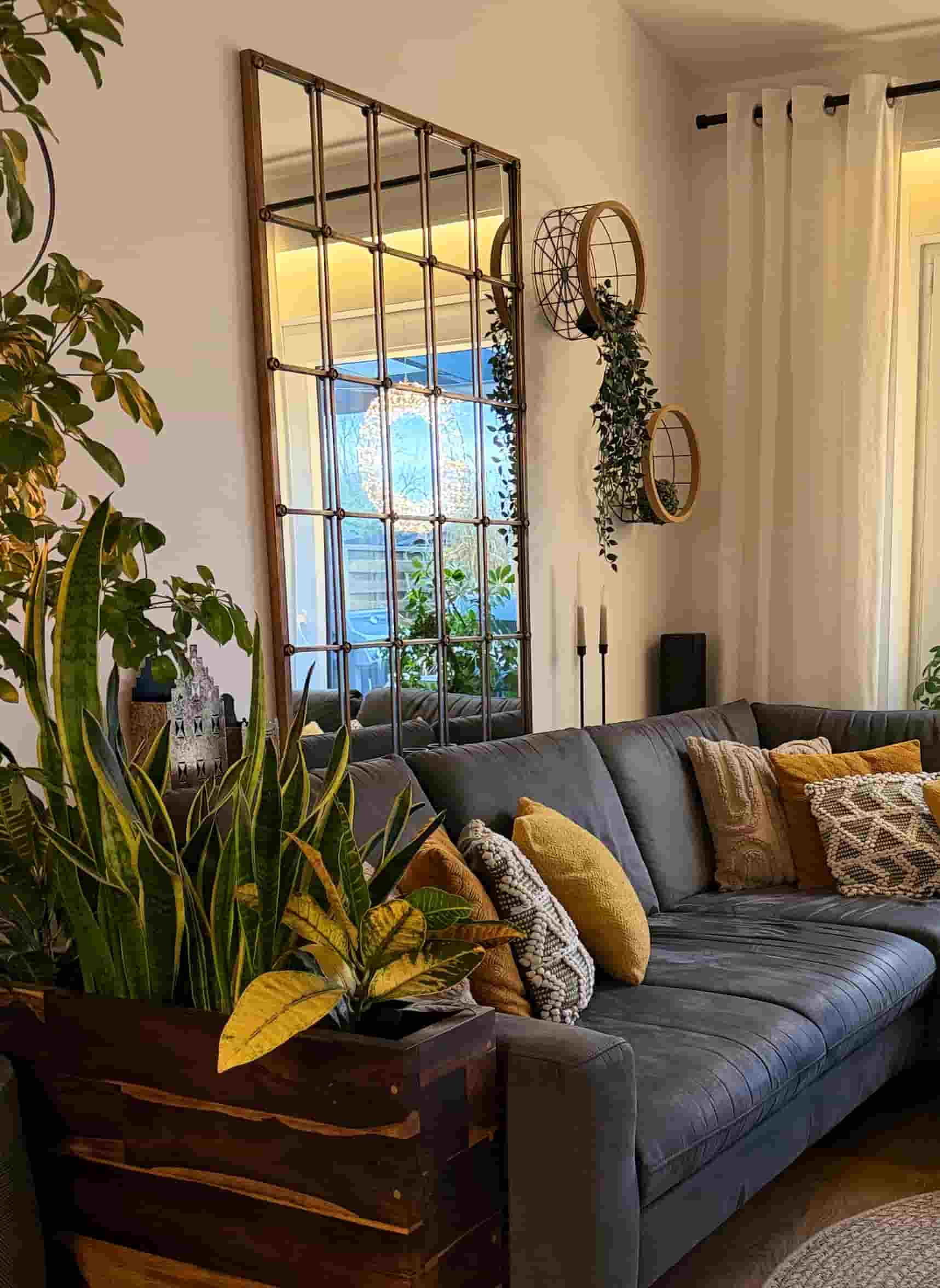 Natürliche Farben im Wohnzimmer mit Sofa, Spiegel und Pflanzen. Einrichtungsgespür bei Kernfokus