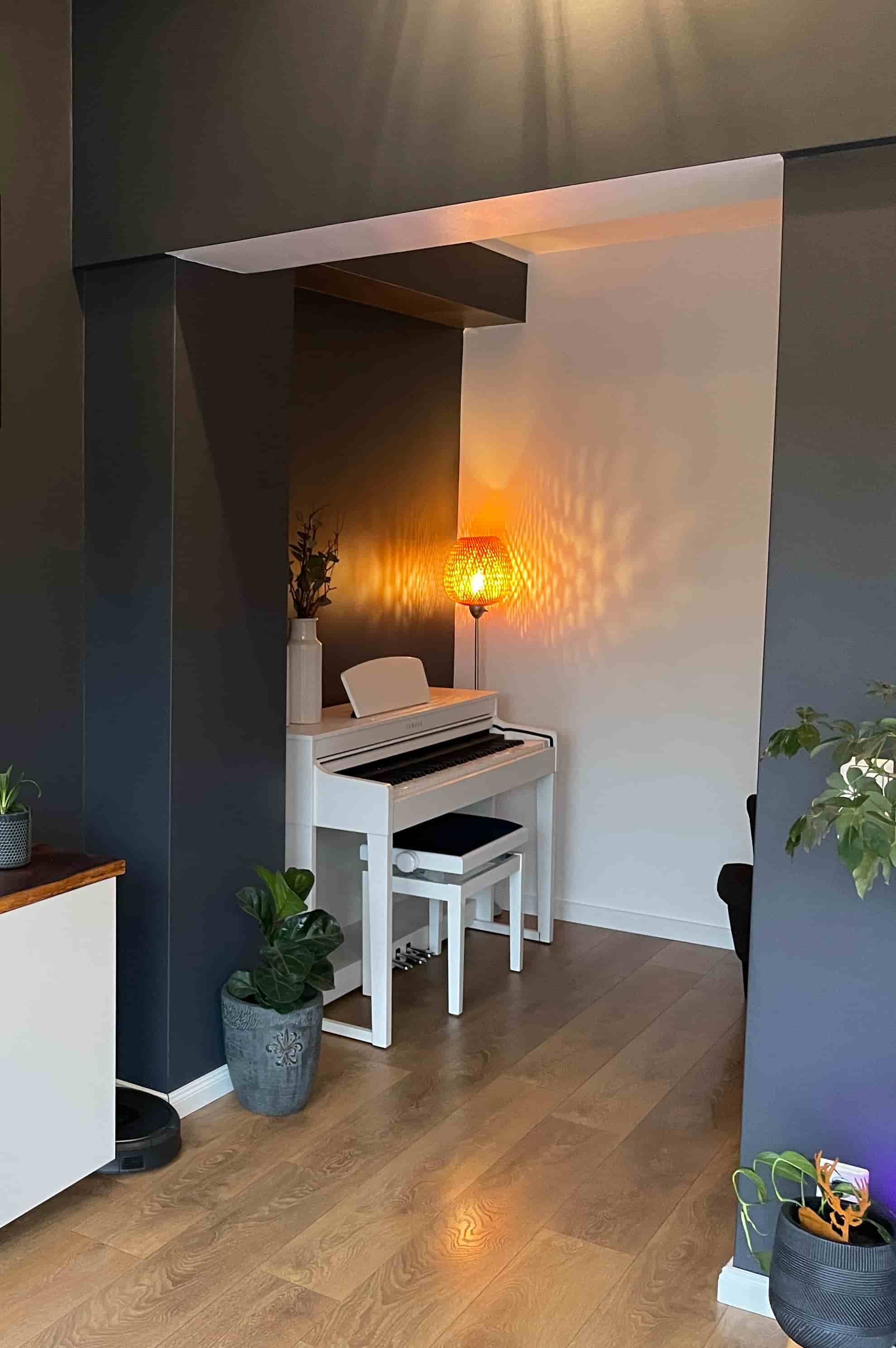 Weißes Klavier in dunklem Raum, warm beleuchtet. Farbkonzepte bei Kernfokus