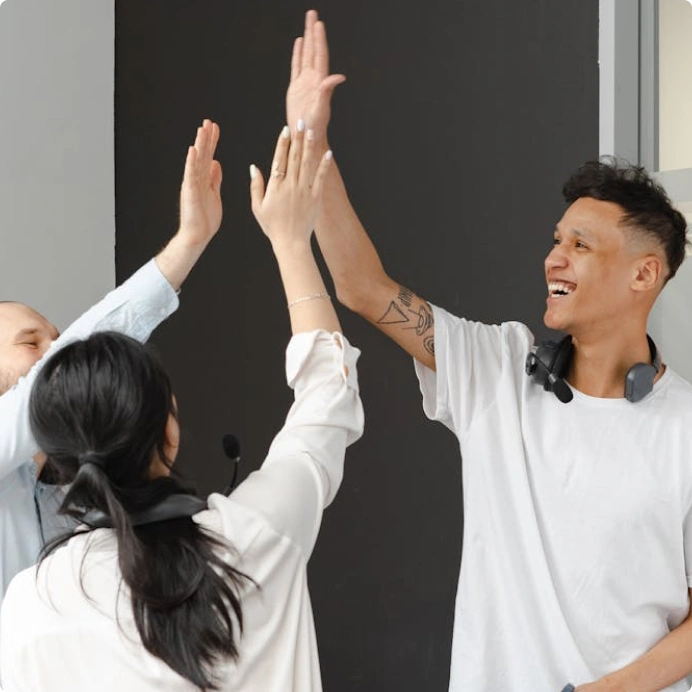 A team in workplace environment giving high-five and celebrating a project