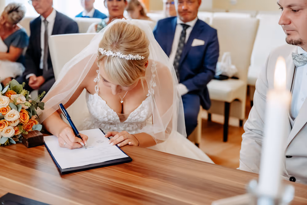 Braut unterschreibt die Heiratsurkunde im Standesamt