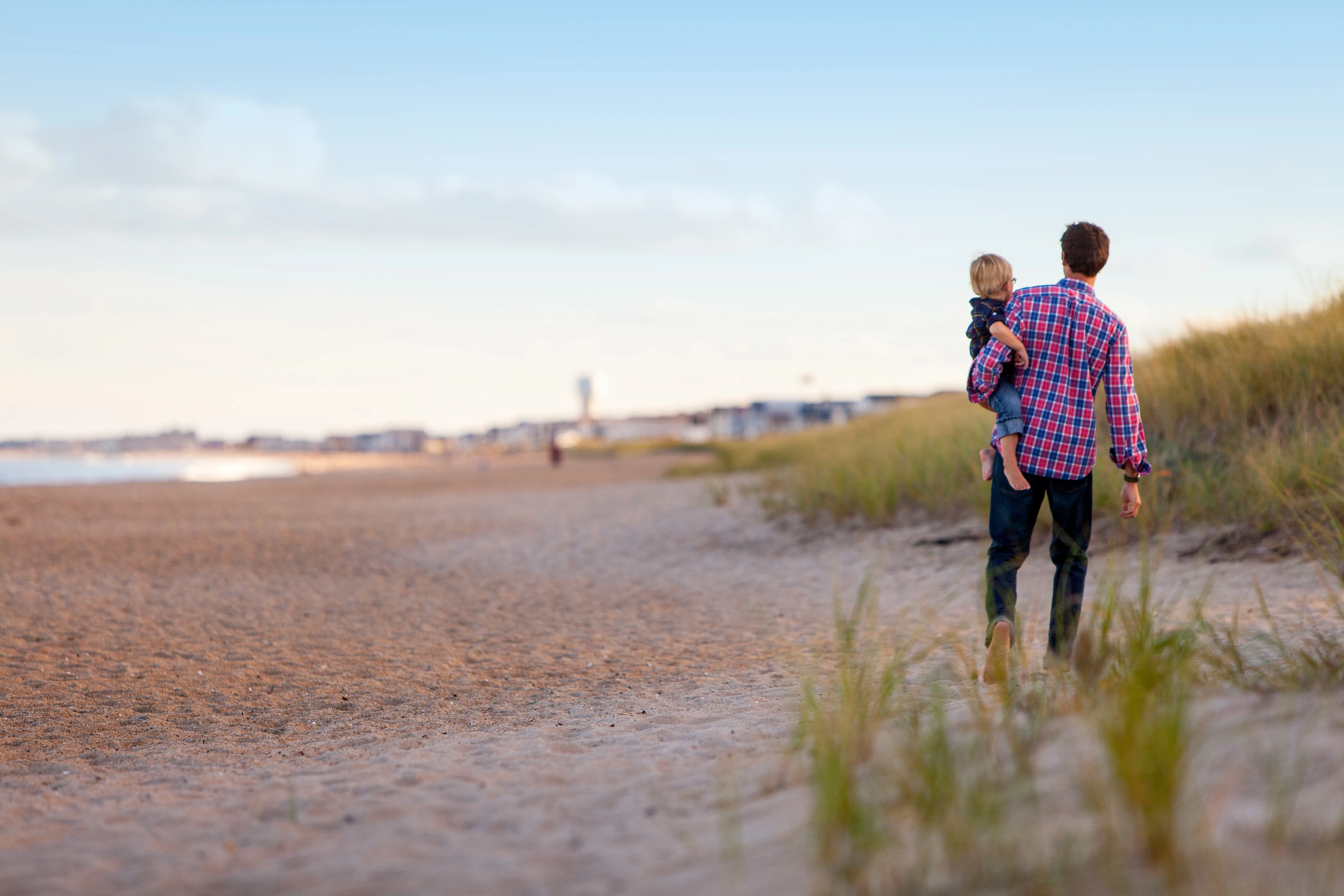 Parent and child walking together on a sandy beach at sunset