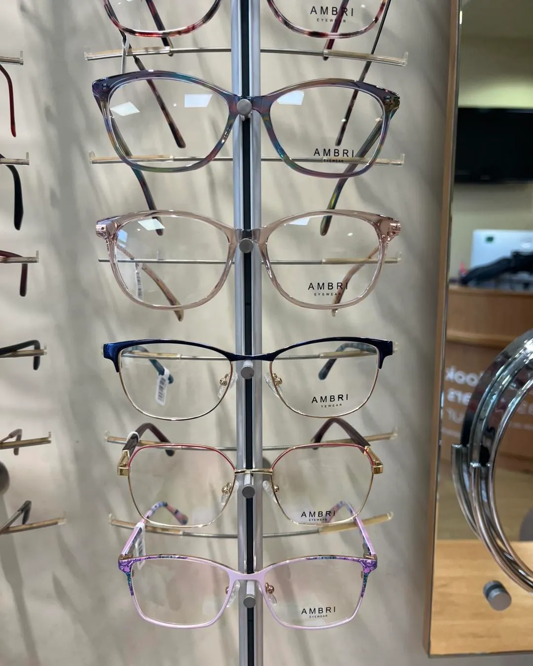 Display of Ambri eyeglasses in various colors and styles on a vertical rack