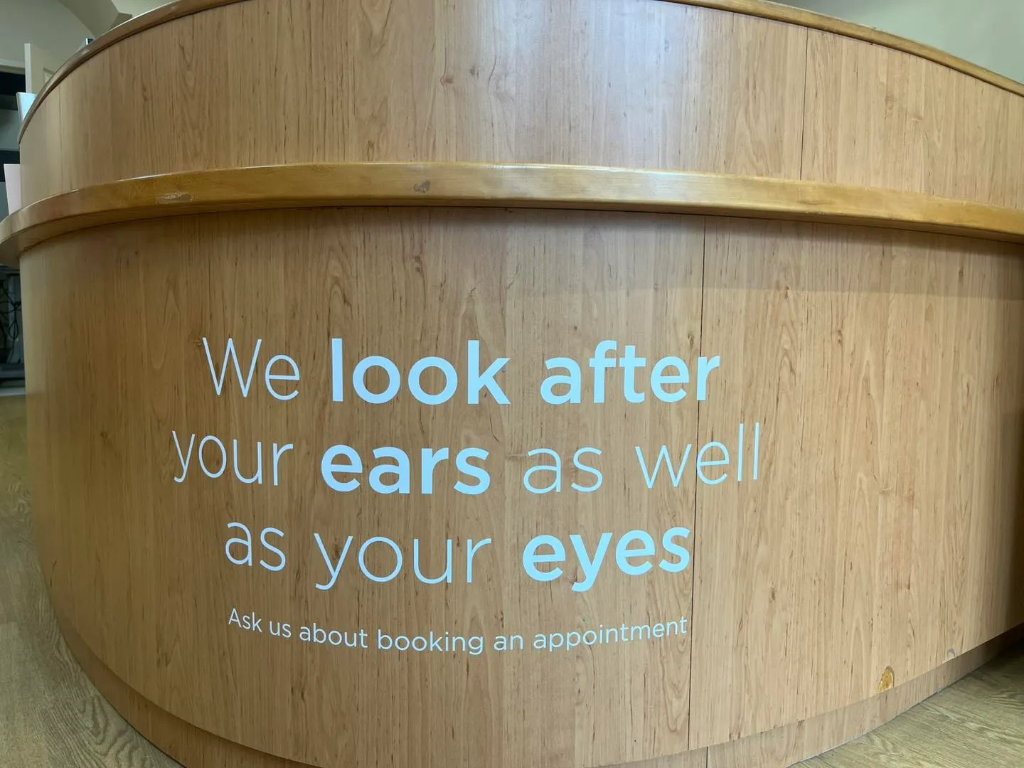 Wooden counter with text about ear and eye care, booking appointment