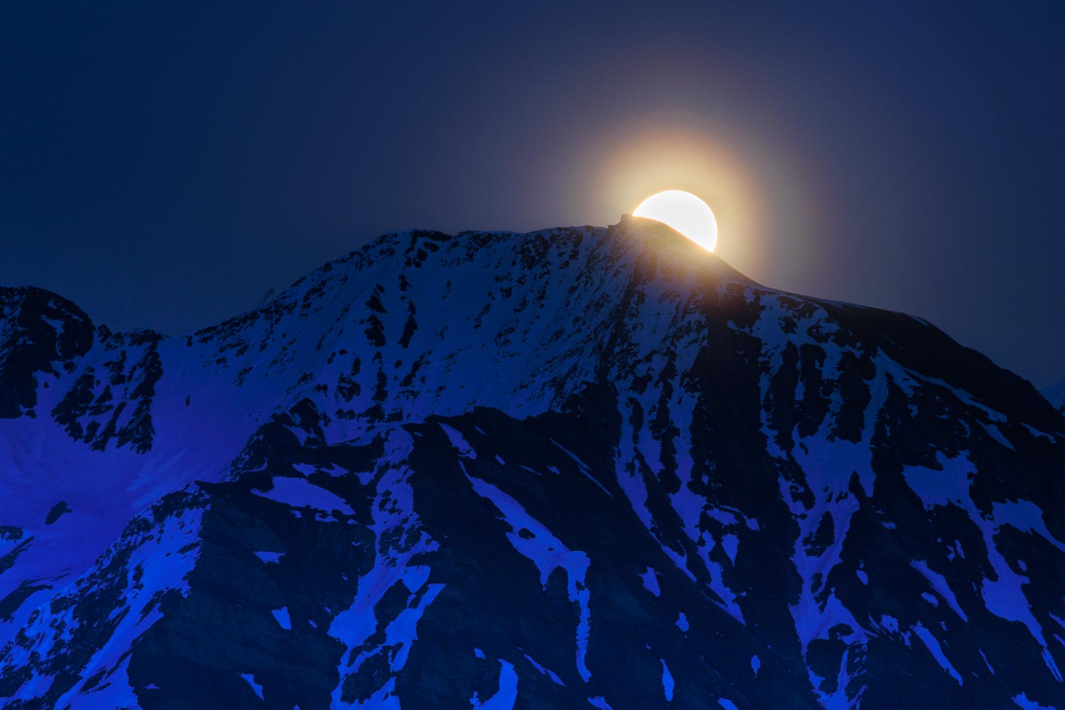 Vollmond flowermoon Aufgang hinter einem Verchneiten Bergspitz