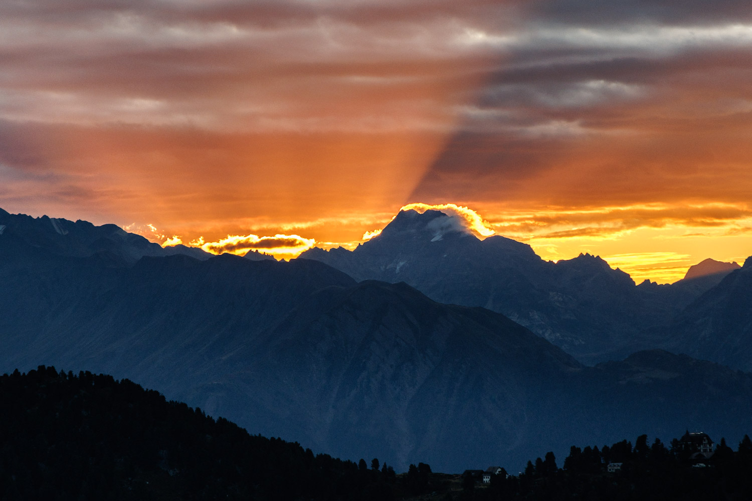 Sonnenstrahlen durchbrechen den Morgenhimmel über den Bergen