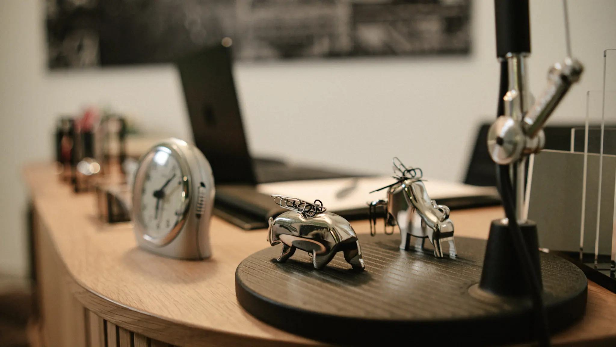 Stilvolle Detailaufnahme eines modernen Schreibtischs mit Uhr und Metallfiguren im Büro – Businessfotografie von L’Étoile Visuals