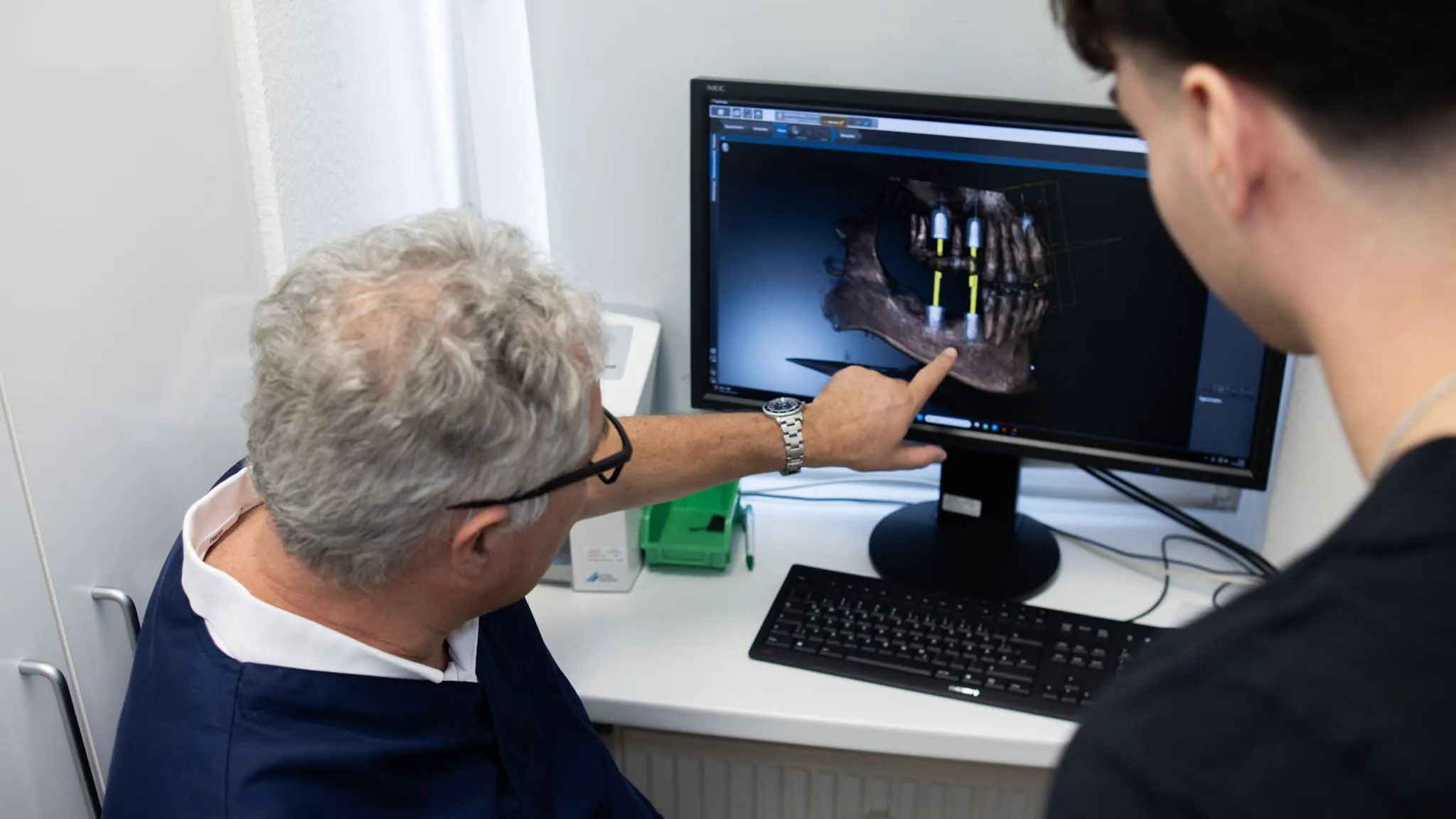 Zahnarzt zeigt die digitale Darstellung eines Unterkiefers mit geplanter Implantatposition.