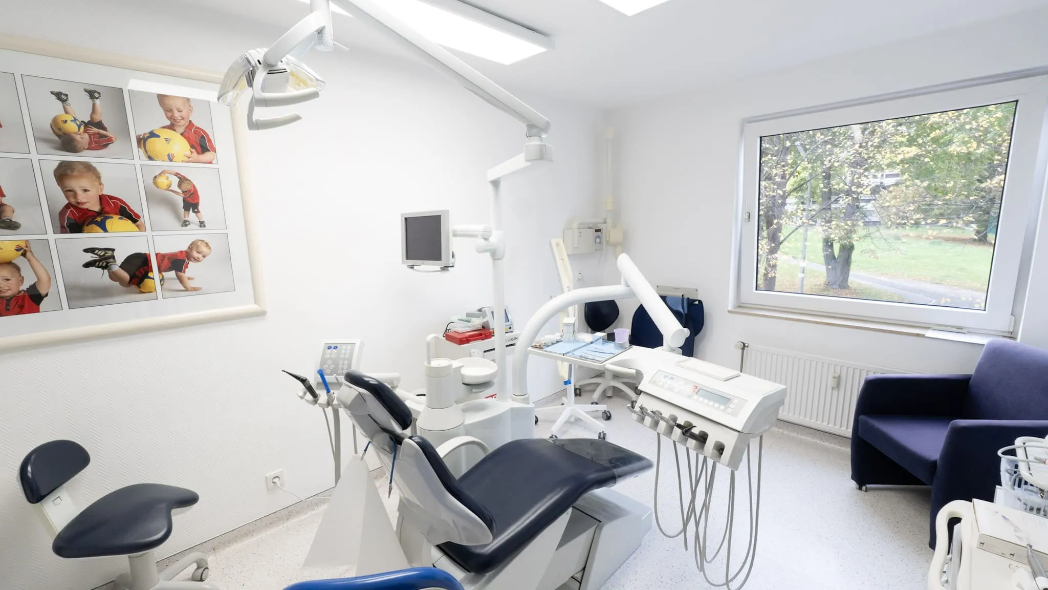 Helles Behandlungszimmer einer Zahnarztpraxis mit moderner Behandlungseinheit und großem Fenster.