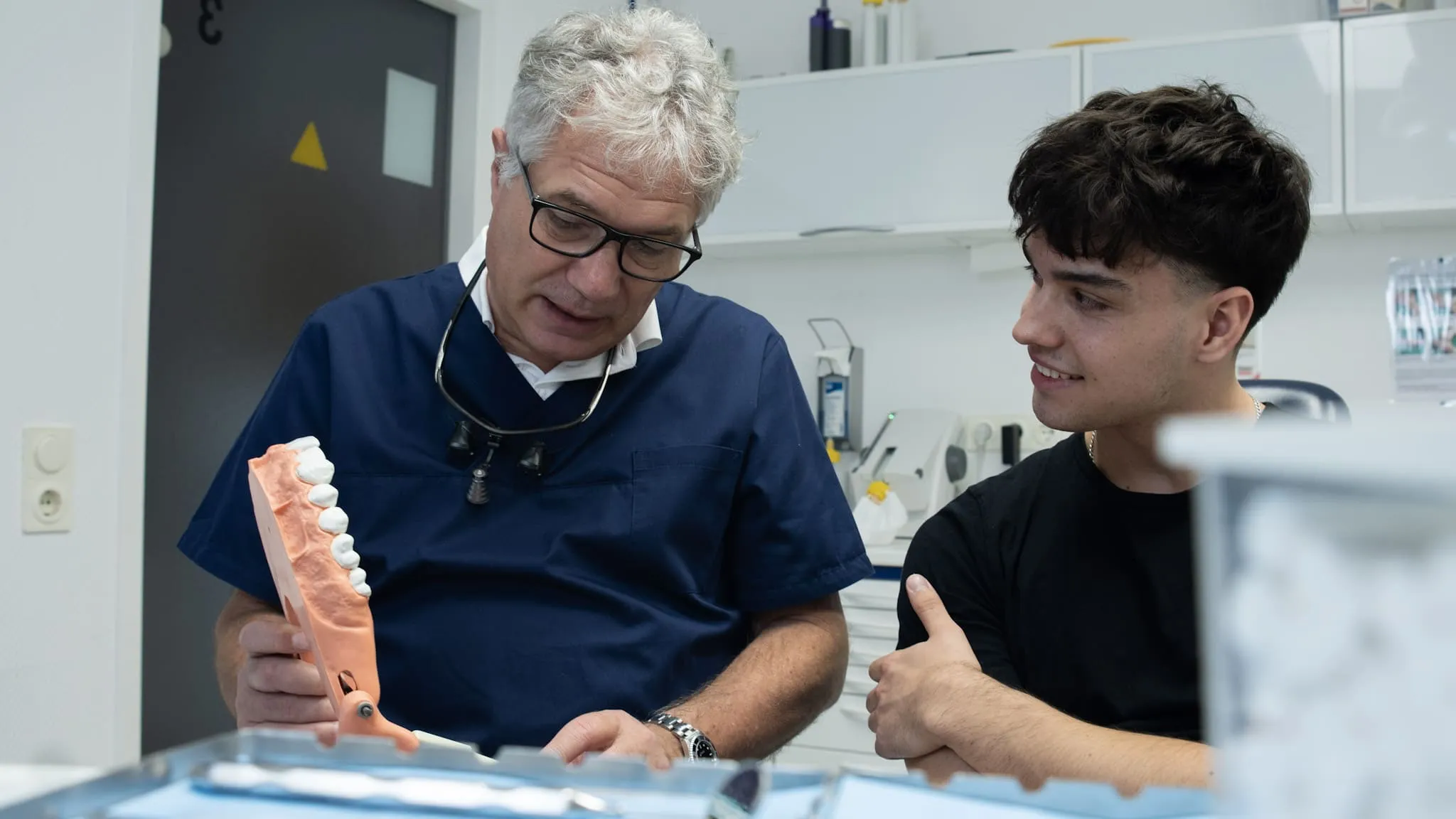 Zahnarzt bespricht Zahngesundheit mit Patient und nutzt Zahnmodell zur Veranschaulichung.