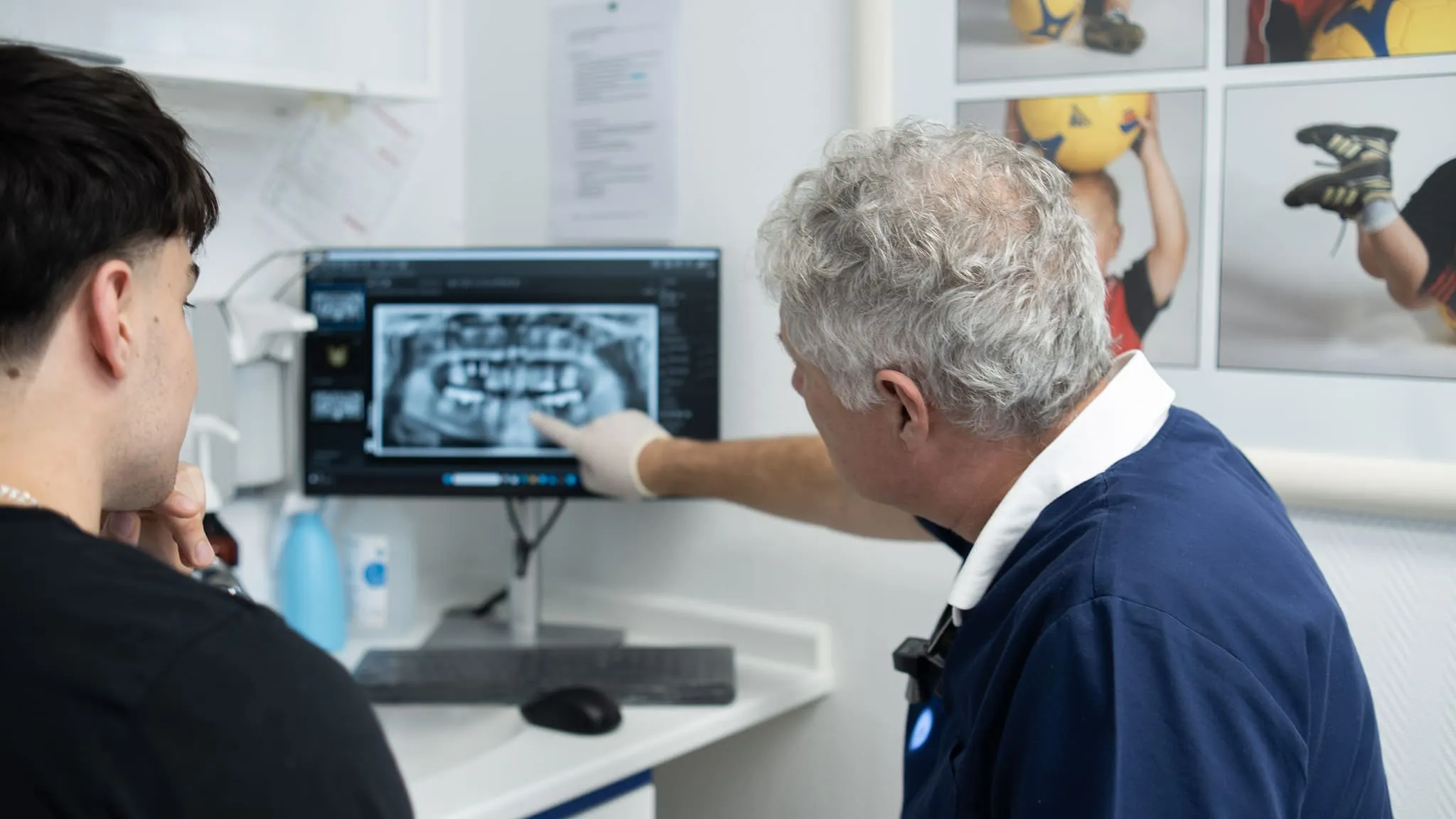 Zahnarzt erklärt einem Patienten ein digitales Röntgenbild am Computer in der Zahnarztpraxis.