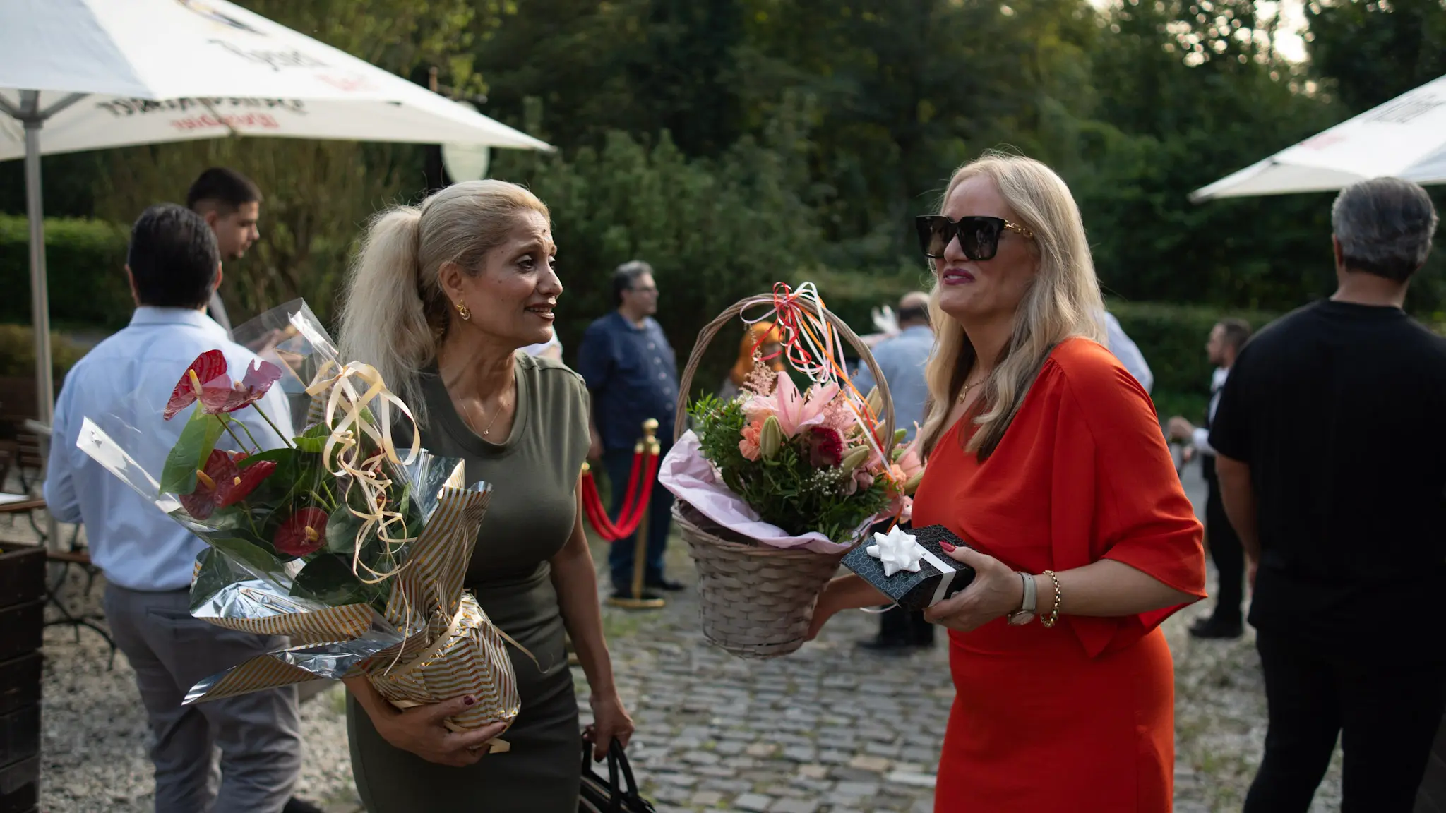 Zwei Gäste überreichen Blumen und Geschenke bei der Eröffnungsfeier in Bonn – emotionale Eventfotografie von LetVis Media