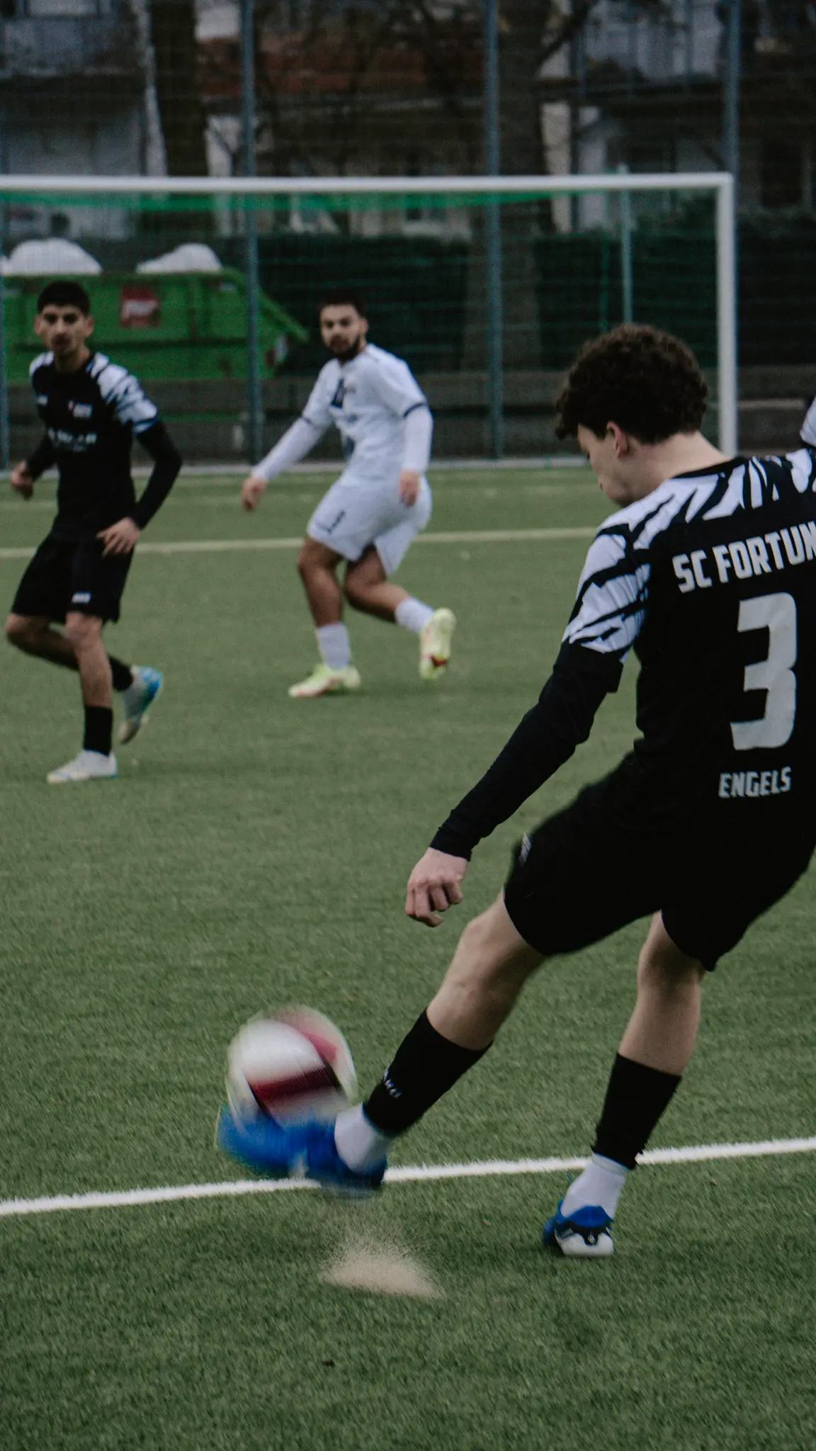 Fußballspieler trifft den Ball im Schussmoment – actionreiche Aufnahme auf dem Spielfeld – Sportfotografie von L’Étoile Visuals