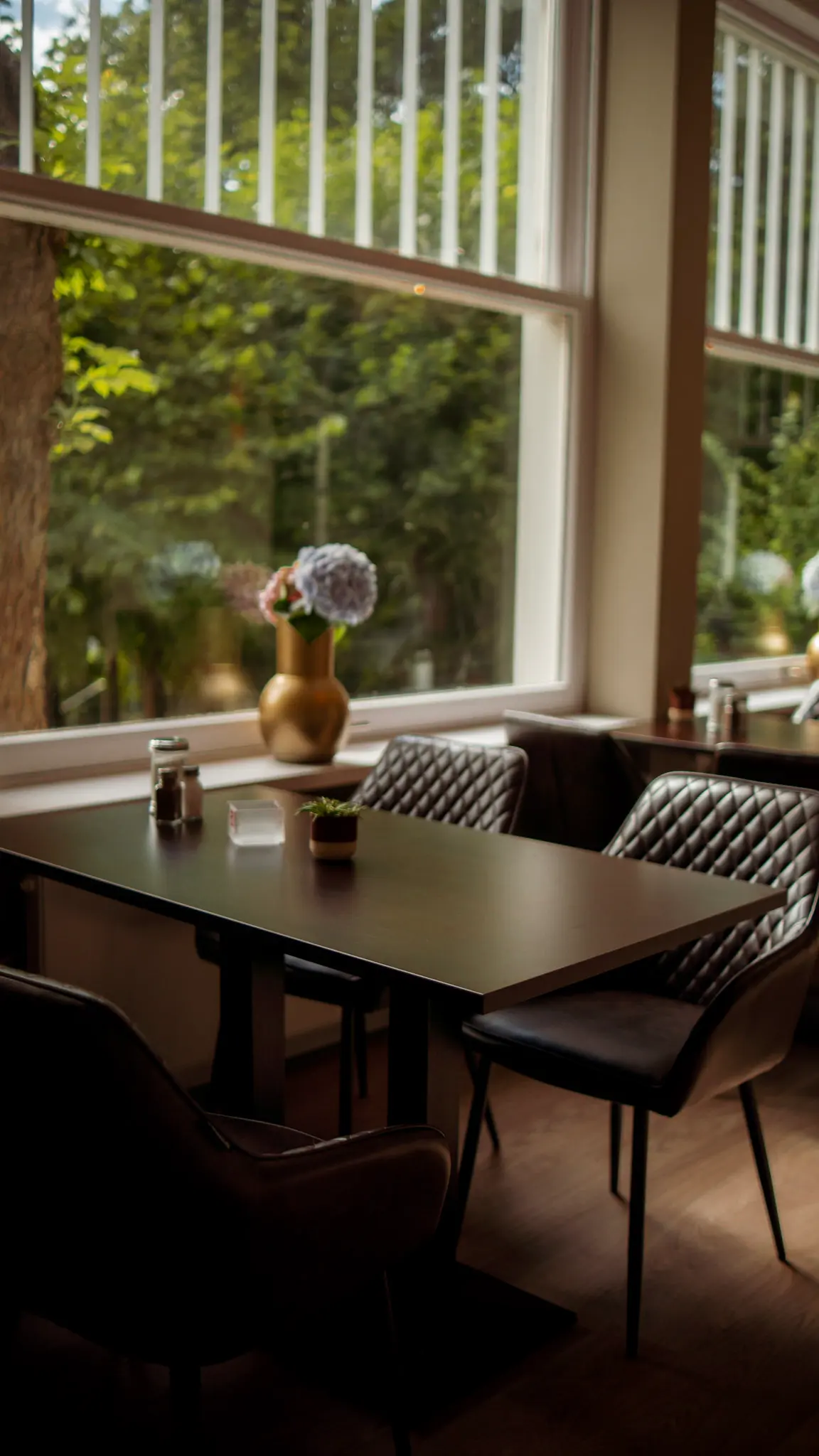 Helles Café-Interior mit modernen Lederstühlen und Blumenvase auf dem Tisch – stilvolle Interiorfotografie – L’Étoile Visuals