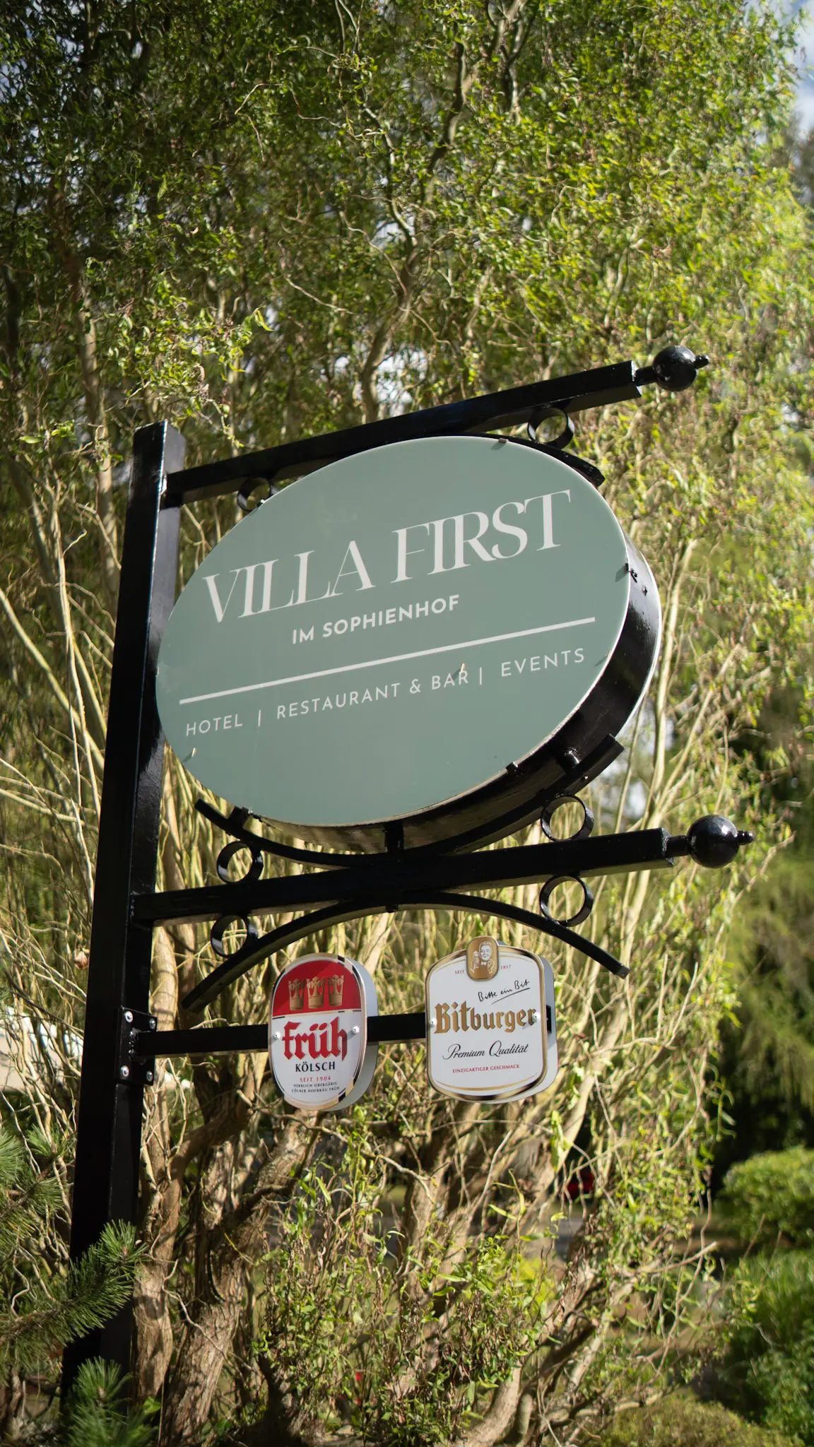Schild der Villa First im Sophienhof mit Logos von Früh Kölsch und Bitburger – Restaurant und Eventlocation – fotografiert von L’Étoile Visuals
