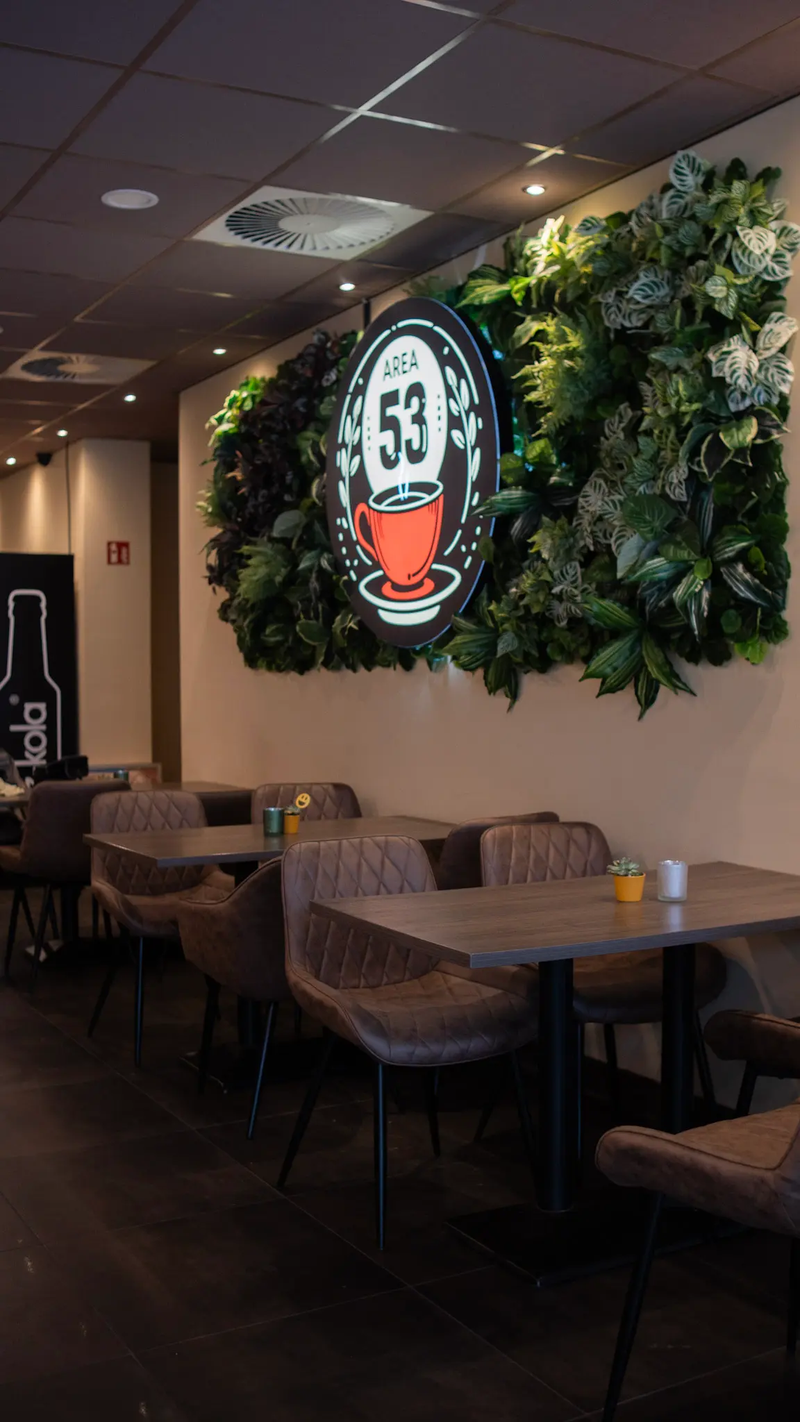 Modernes Café Interior im Area 53 mit Pflanzenwand und gemütlichen Sitzbereichen – professionell fotografiert von L’Étoile Visuals
