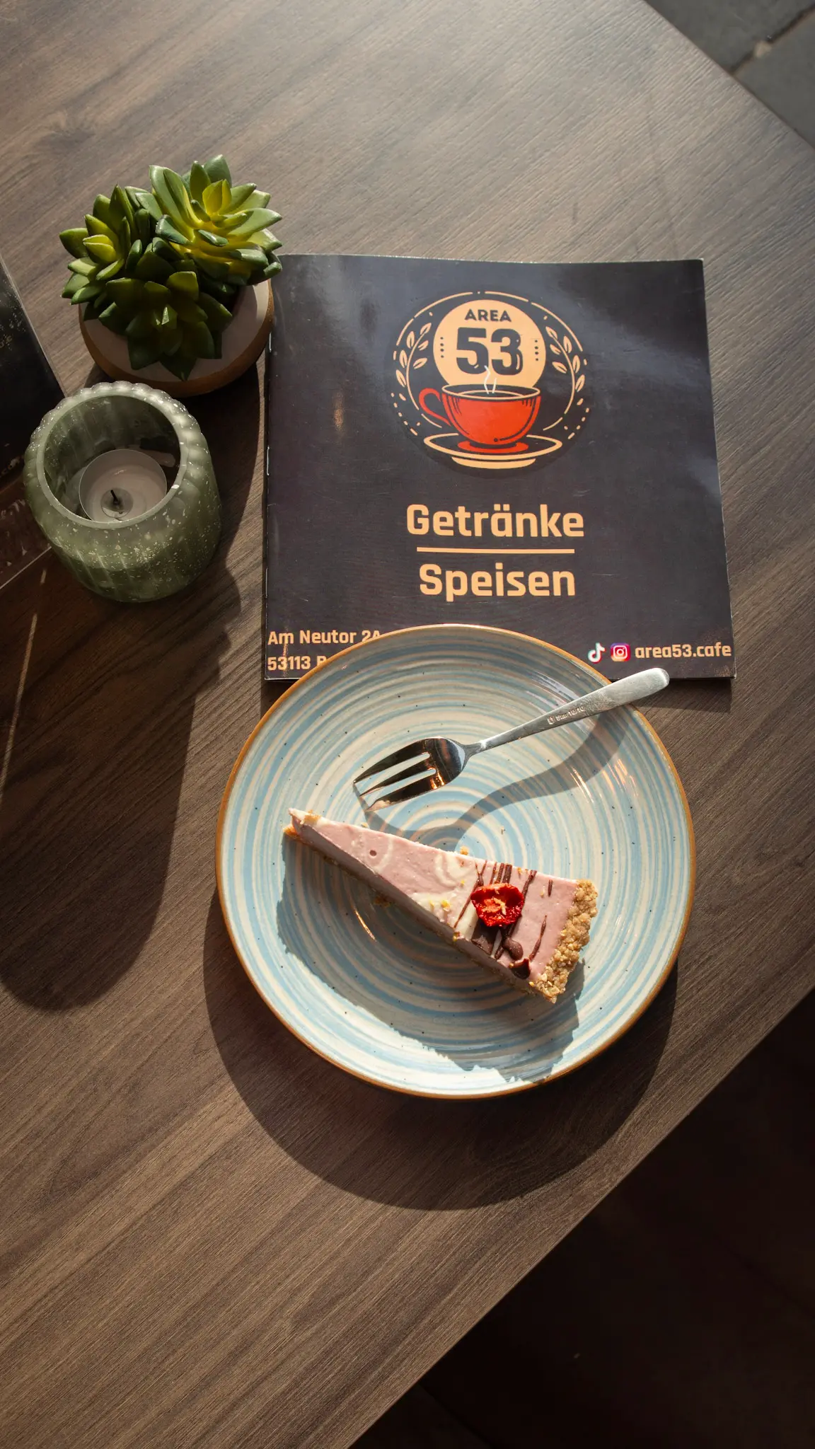 Stück Kuchen auf Teller neben der Speise- und Getränkekarte des Area 53 Cafés – Foodfotografie von L’Étoile Visuals