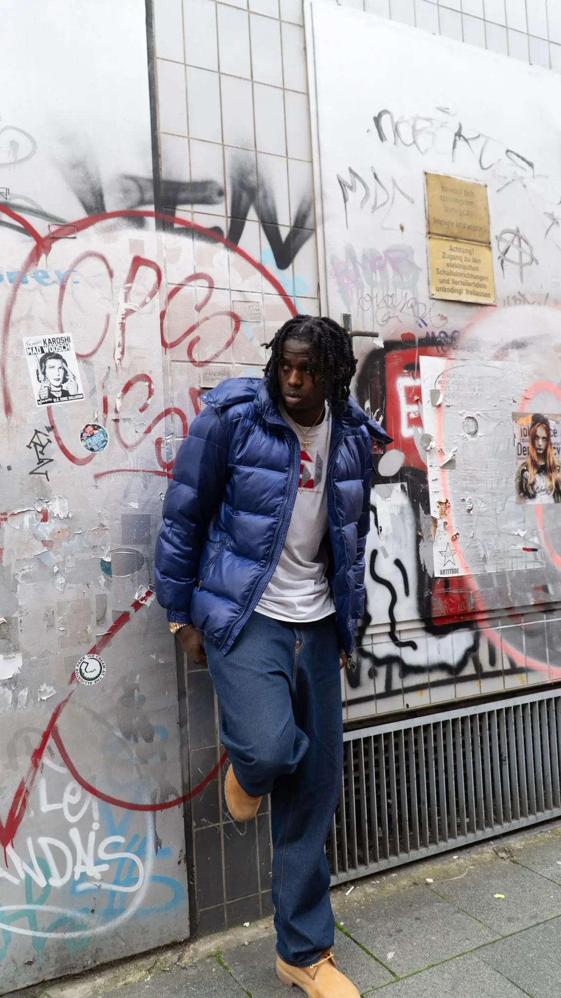 Streetwear-Fotoshooting – Model in blauer Pufferjacke, Jeans und Boots posiert vor Graffiti-Wand, aufgenommen von L’Étoile Visuals