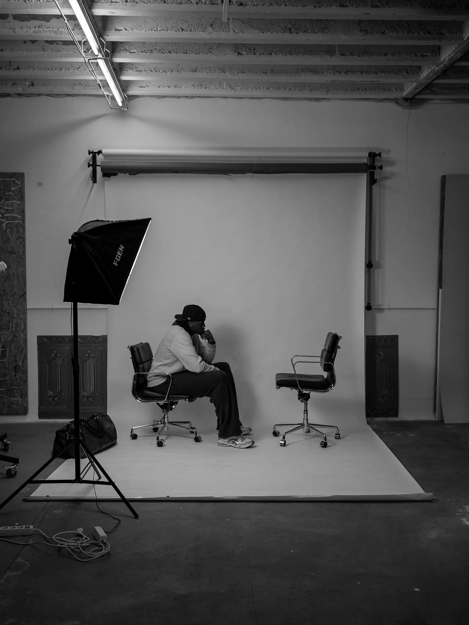 Schwarzweißaufnahme im Fotostudio – Mann sitzt nachdenklich auf Stuhl, gegenüber ein leerer Stuhl, künstlerische Darstellung von Selbstreflexion, aufgenommen von L’Étoile Visuals