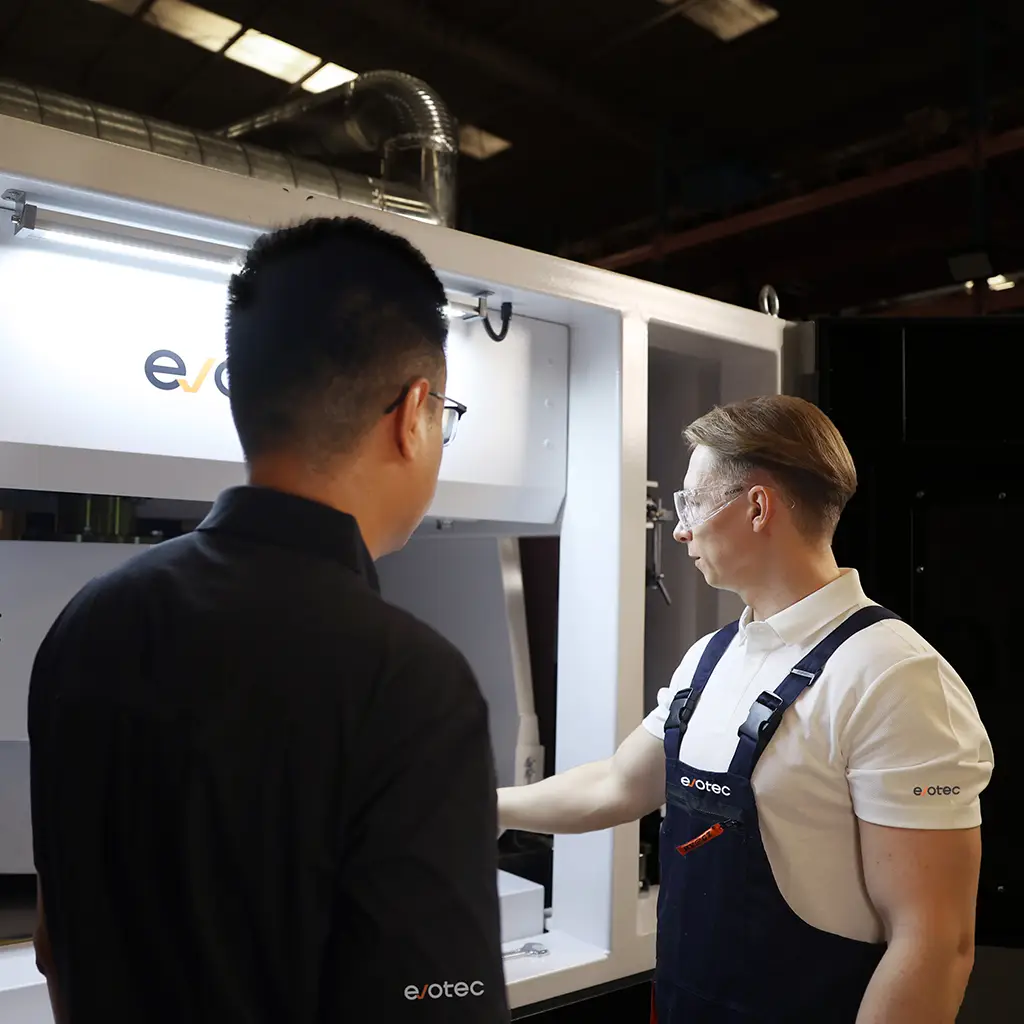Dois funcionários da Evotec verificando uma máquina de rebarbação Evotec