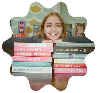A Penguin Books UK employee resting her heads and hands on a pile of books.