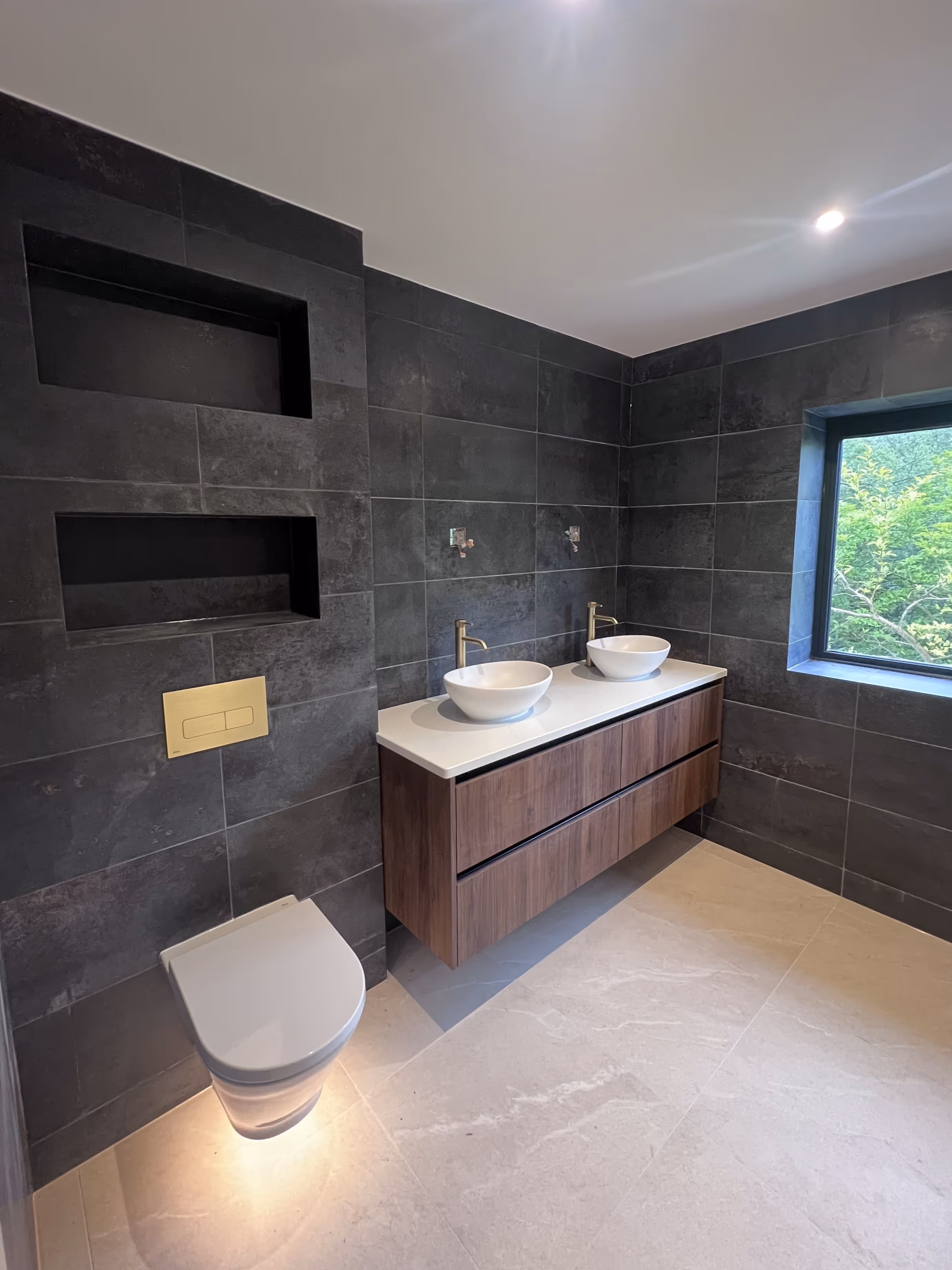 Modern bathroom with black wall tiles and grey floor tiles