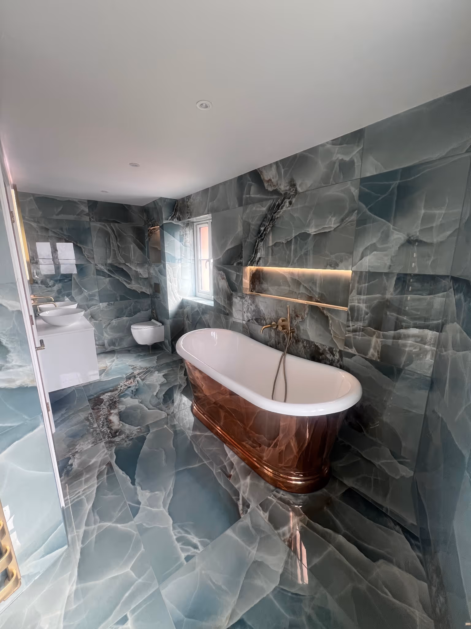 Luxury bathroom featuring unique blue wall and floor tiles and a freestanding bathtub