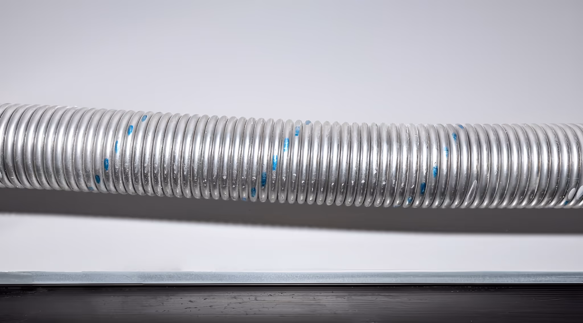 Close-up of a silver garage door torsion spring with blue paint markings.