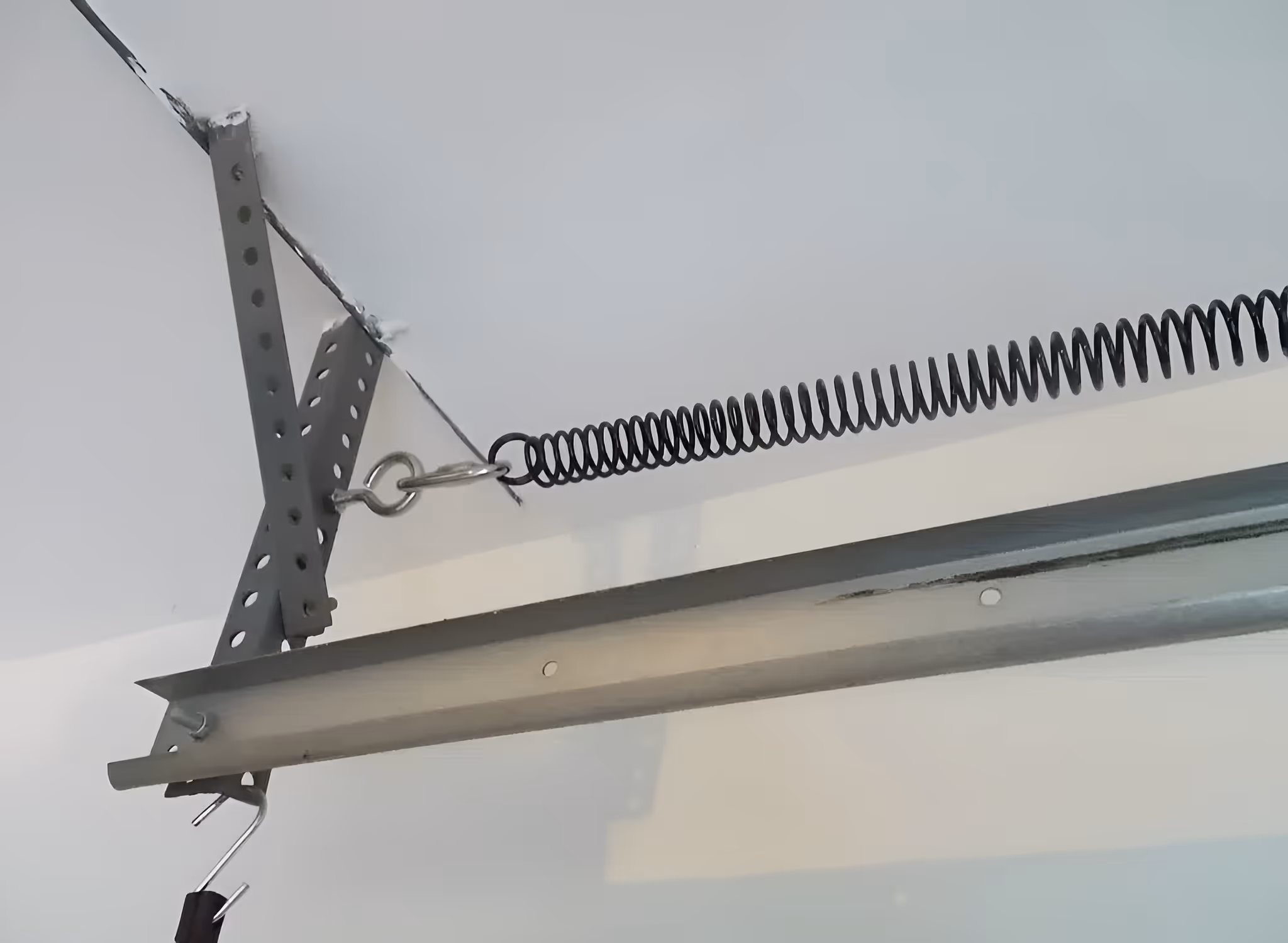 Side-mounted extension spring attached to a horizontal garage door track.