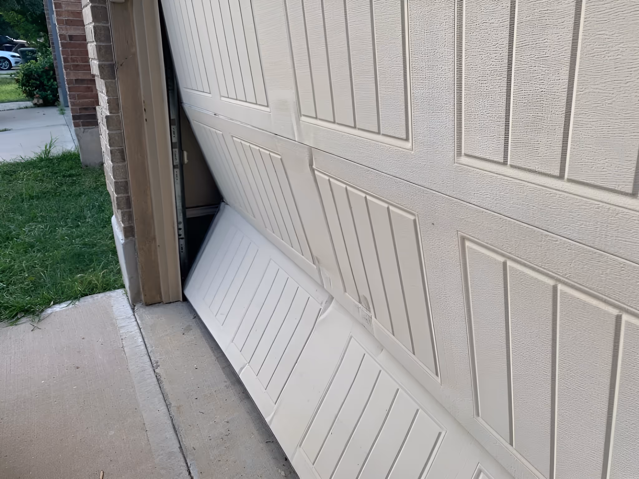 Garage door buckled outward at the bottom after impact.