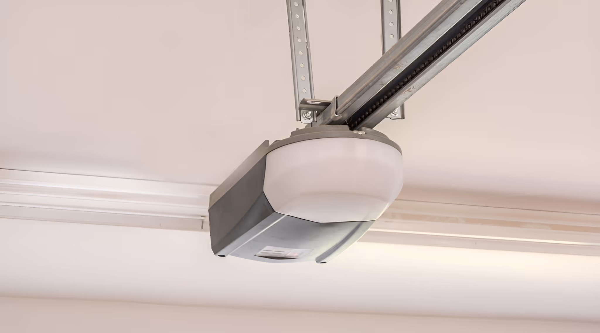 garage door opener mounted on the ceiling, with a light fixture integrated into the unit. The rail system extends from the opener along the ceiling.