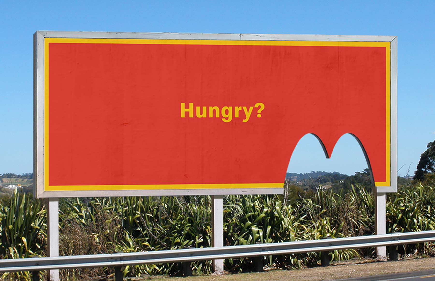 Billboard with the word 'Hungry' written on it and a bite cut out of it in the shape of the McDonalds logo.