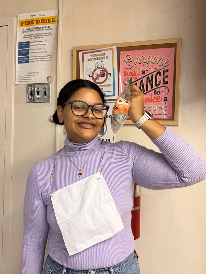 Student smiling and holding a phone to their ear in a hallway