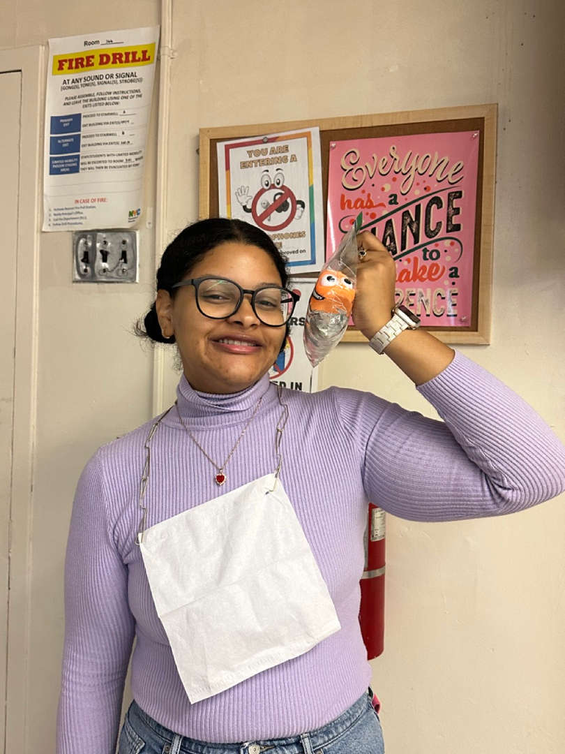 Student smiling and holding a phone to their ear in a hallway