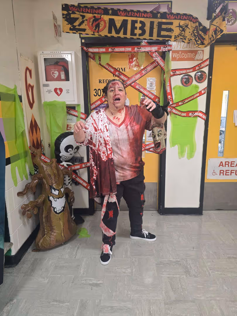 Student in a Halloween costume posing in a decorated hallway.