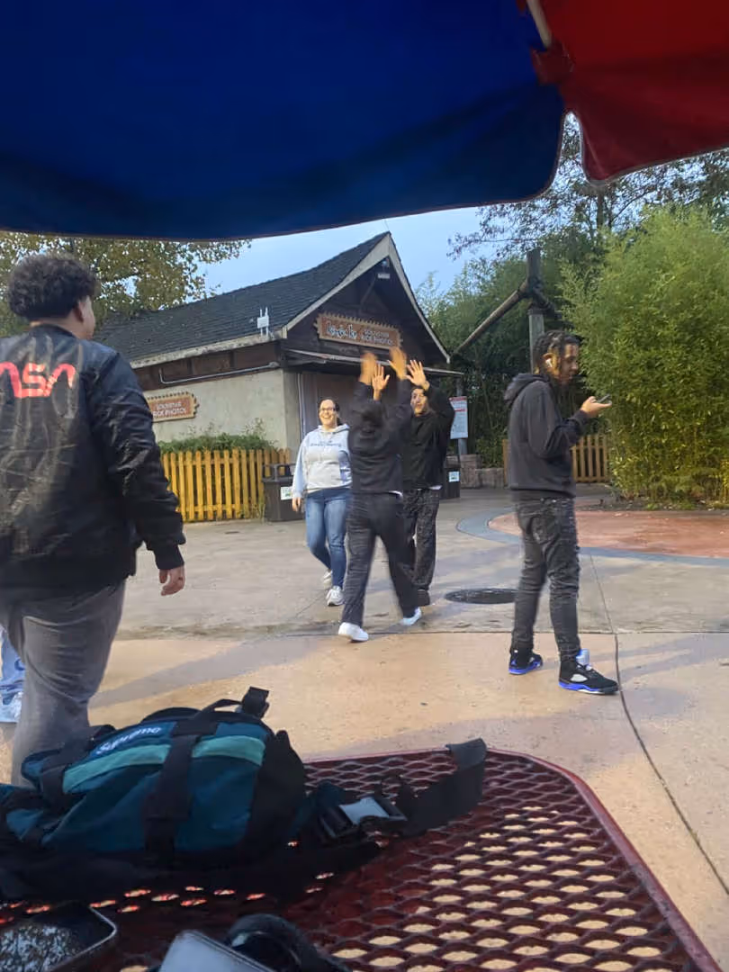 Students walking outdoors near picnic tables.