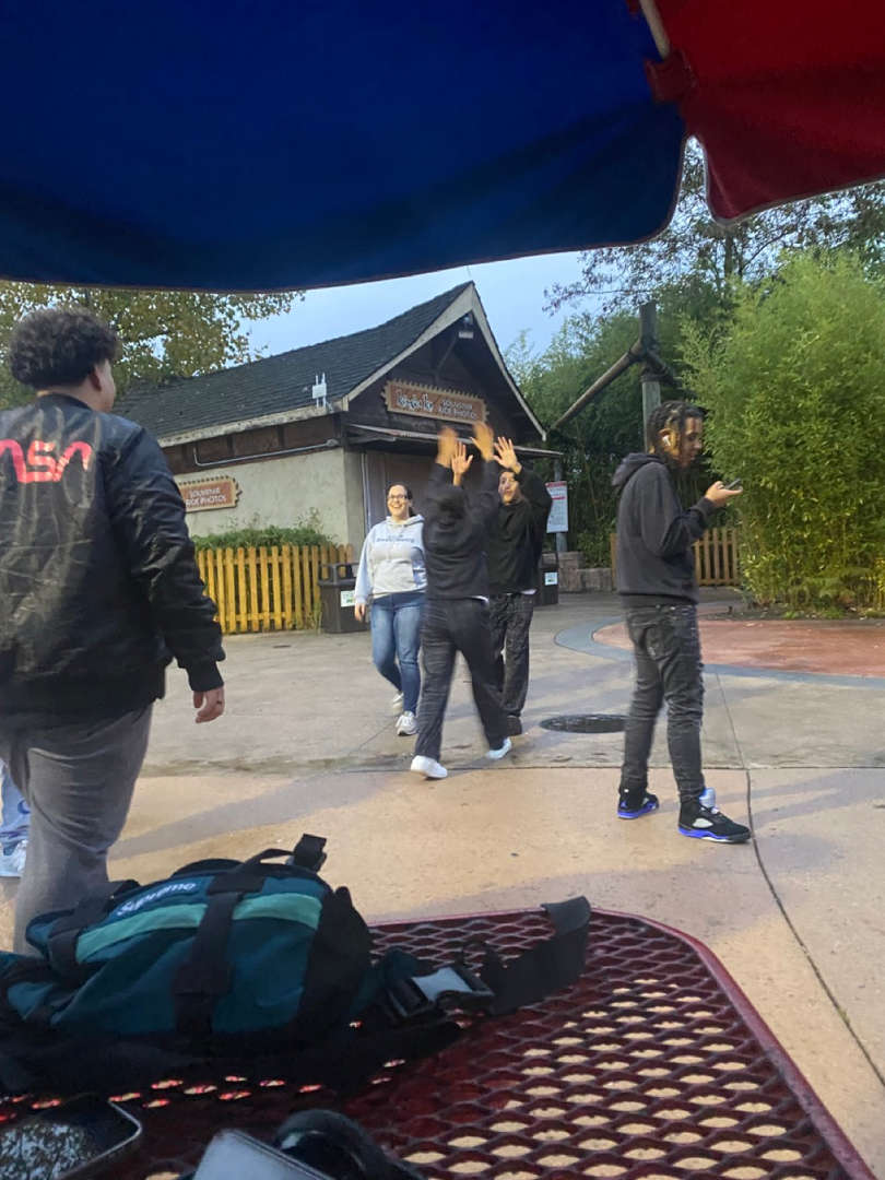 Students walking outdoors near picnic tables.