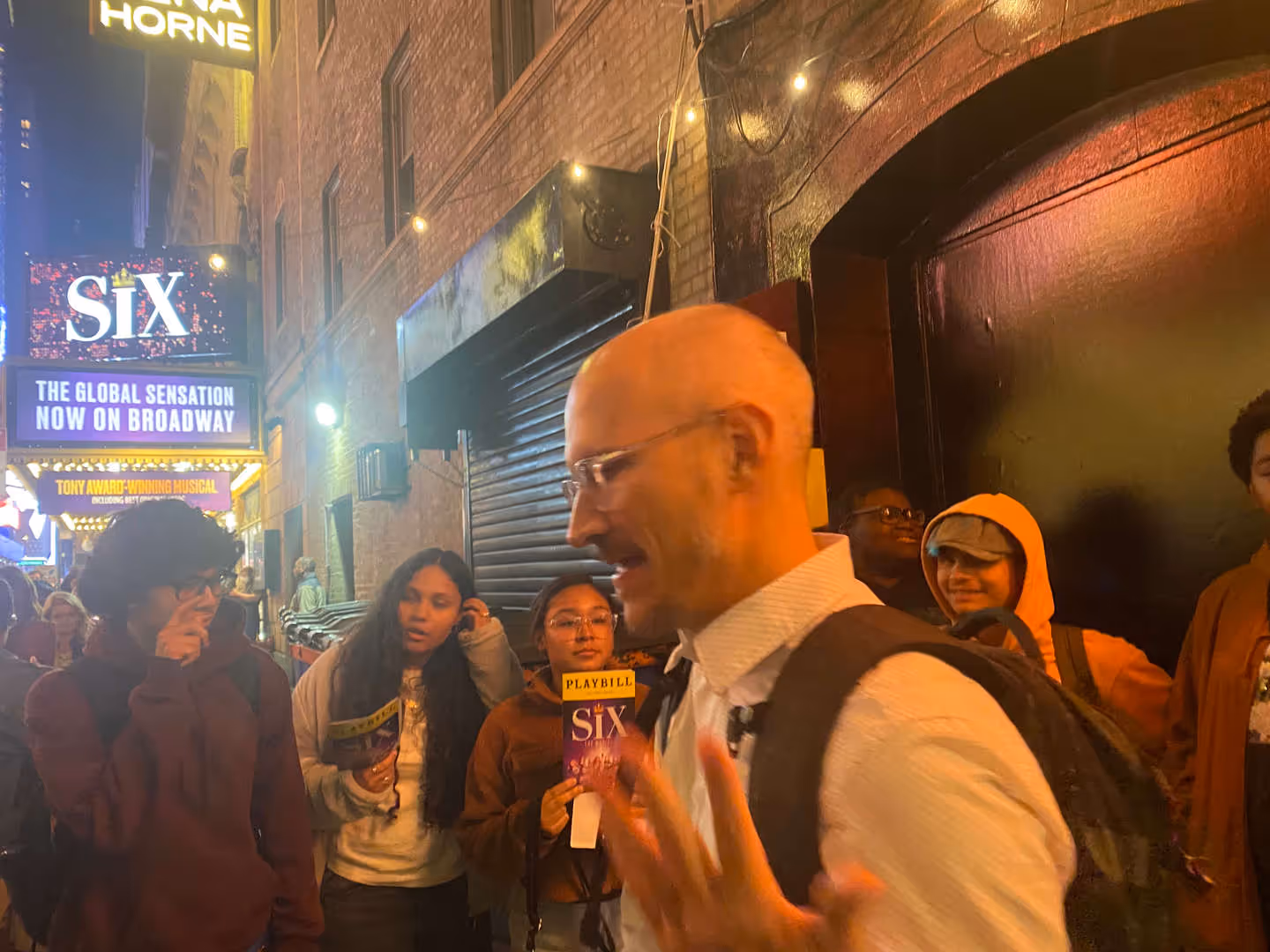 Group of people gathered outside a theater at night