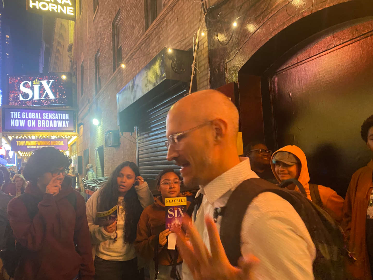 Group of people gathered outside a theater at night