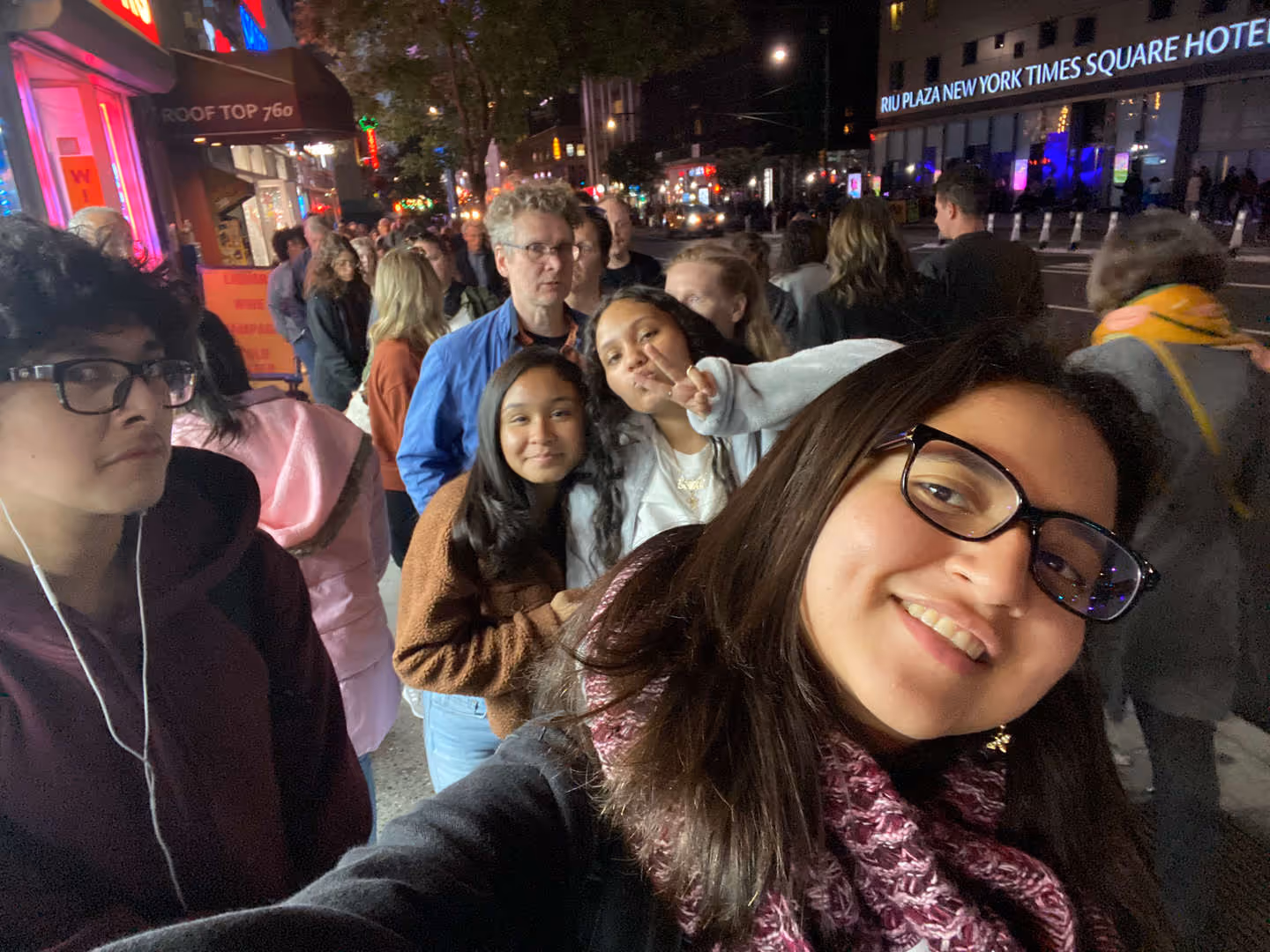 Group of students smiling and taking a selfie at night in the city.