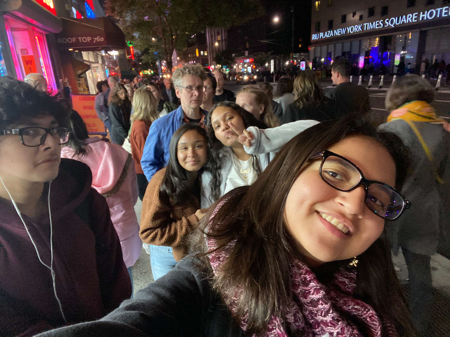Group of students smiling and taking a selfie at night in the city.