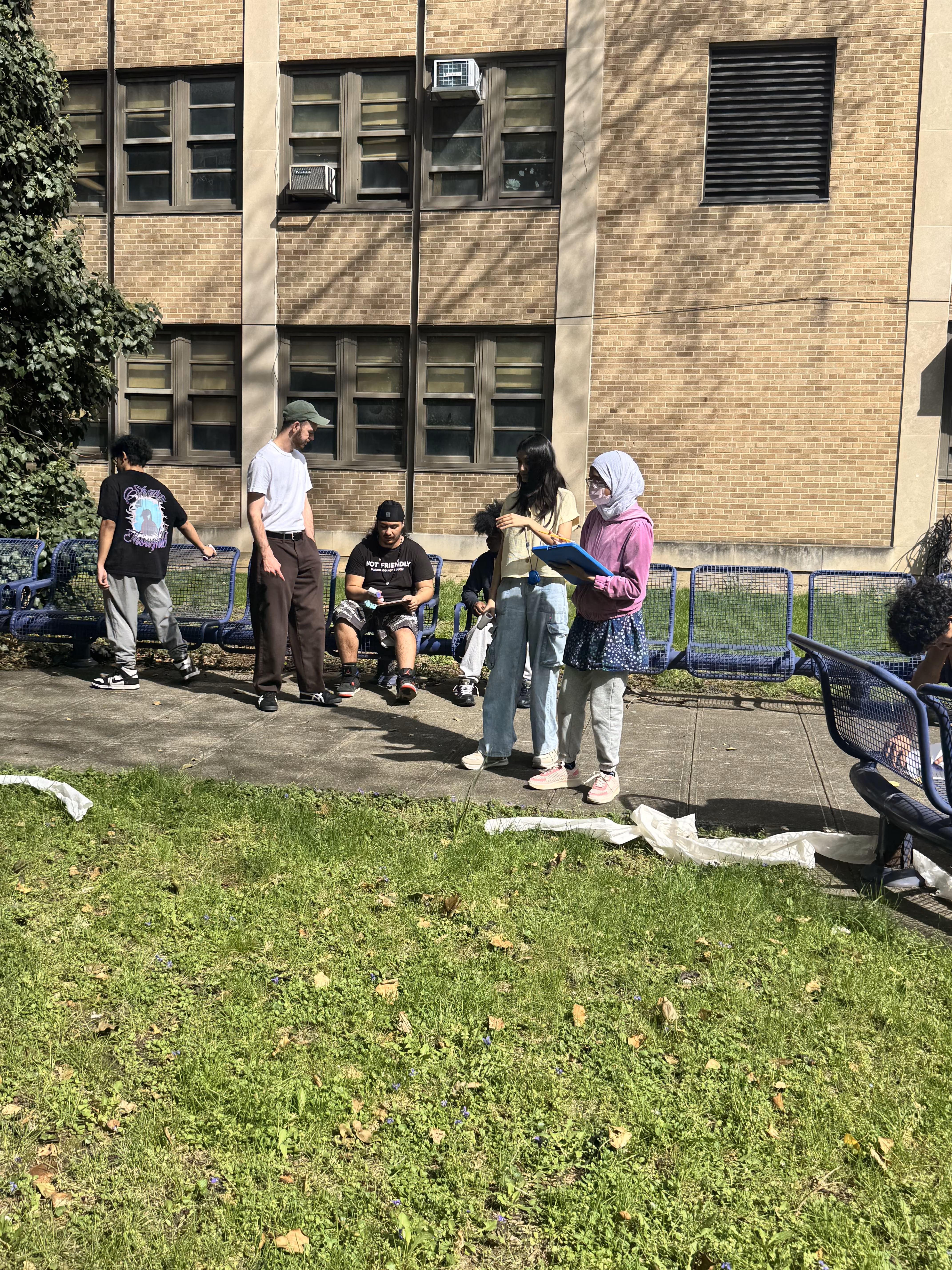 Students gather on school lawn with brick building