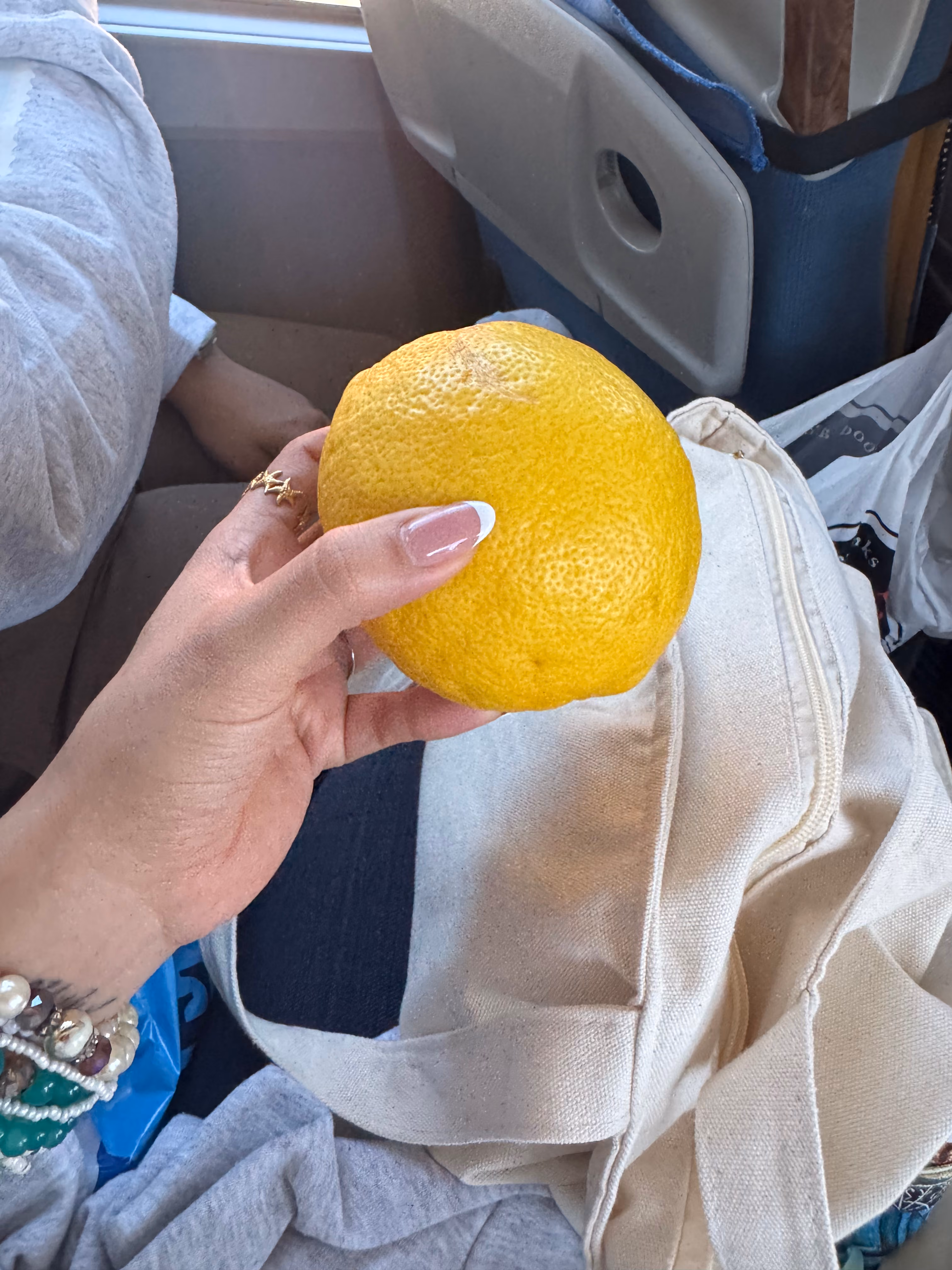 Student holding a large grapefruit on an airplane