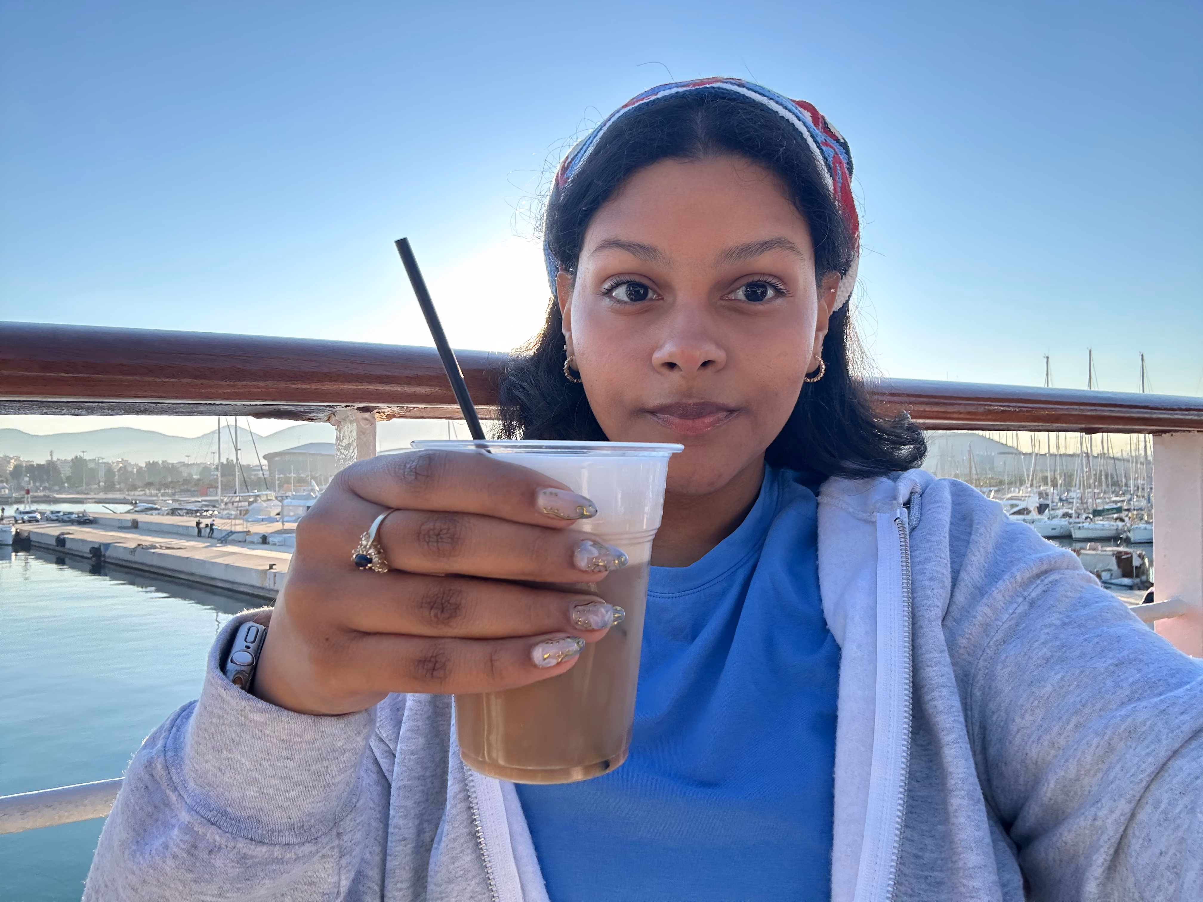 Student holding iced coffee at marina with boats